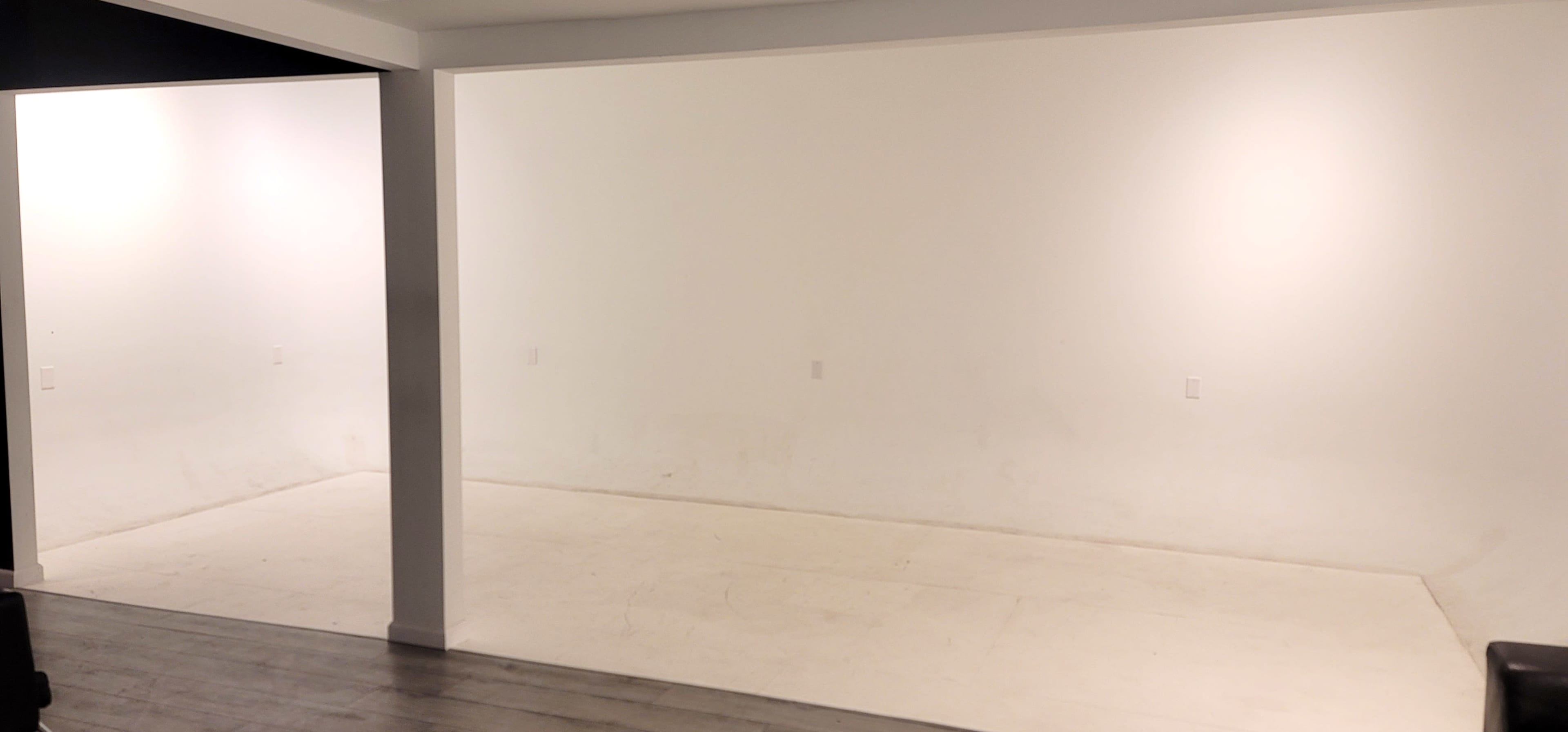 A spacious room with stark white walls and a bare floor.