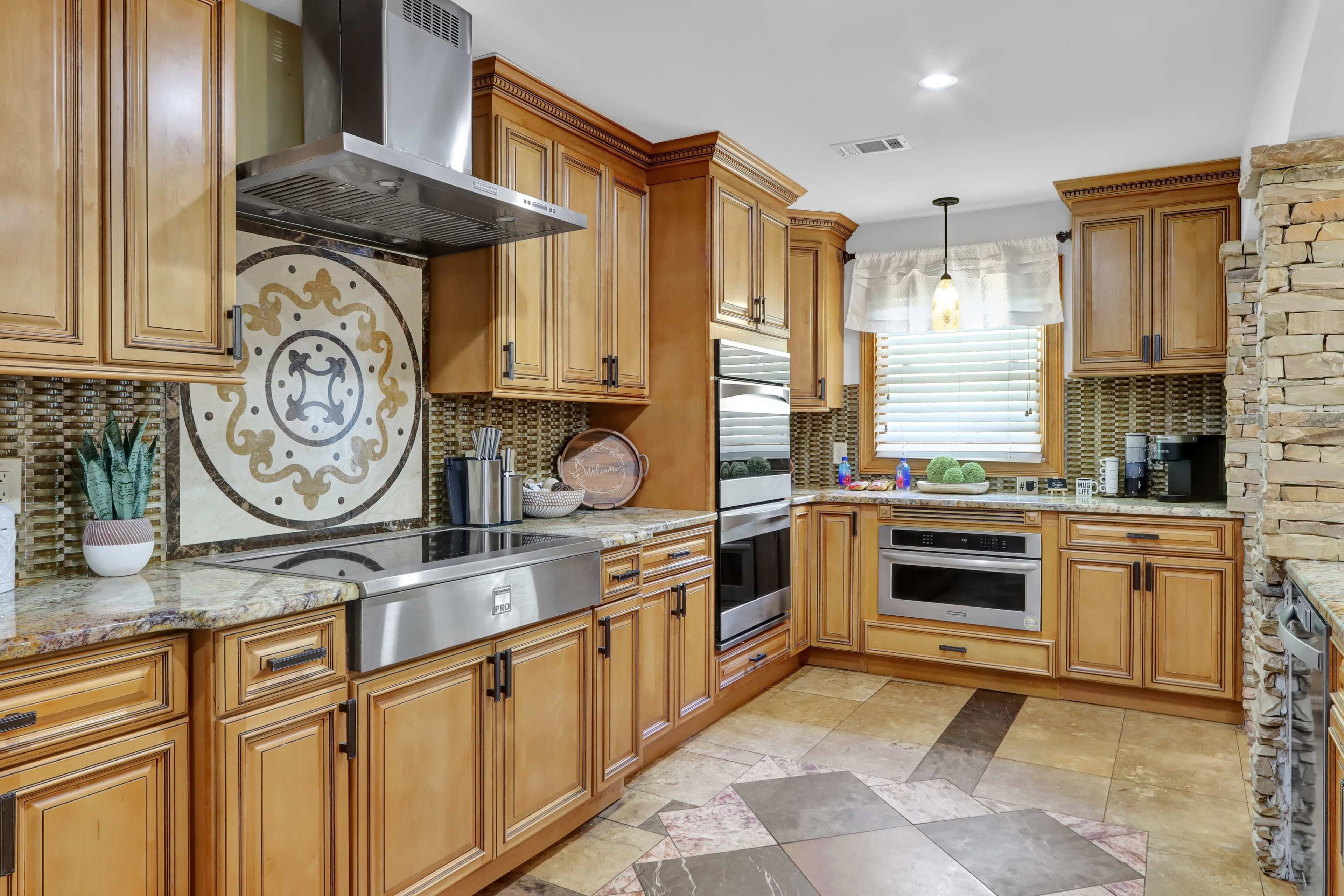 The kitchen features wooden cabinetry, a large stainless steel sink, and a decorative tile backsplash with a circular design.