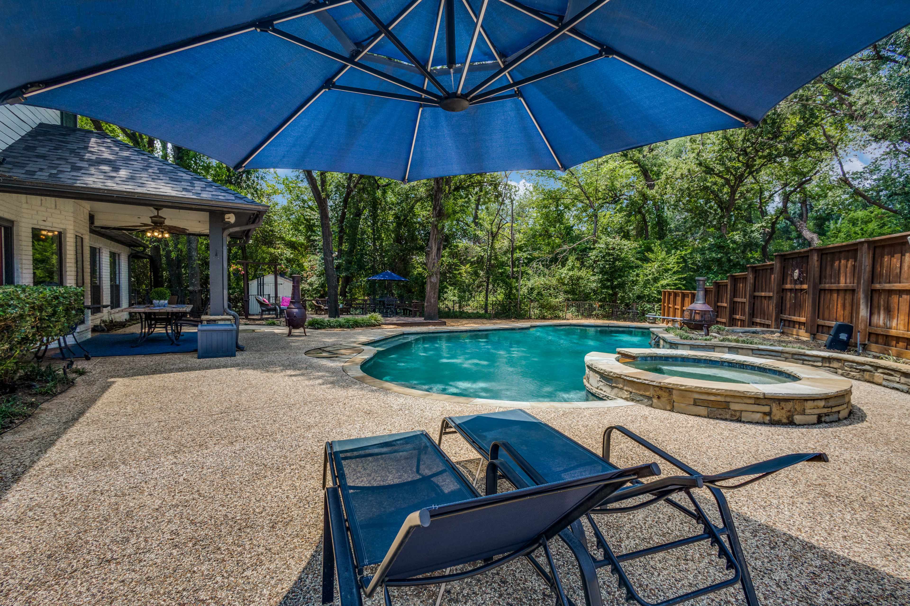 The image shows a backyard pool area with a sunshade, lounge chairs, and a well-maintained landscape.