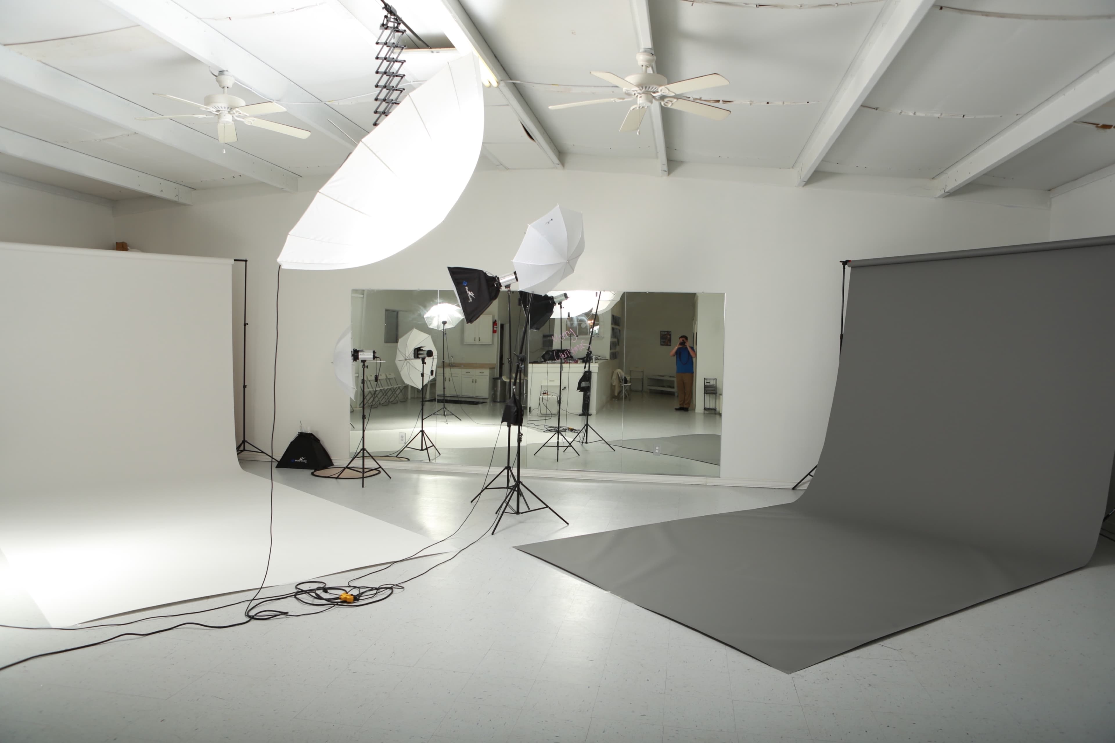 A photography studio with multiple backdrops, lighting equipment, and mirrors.
