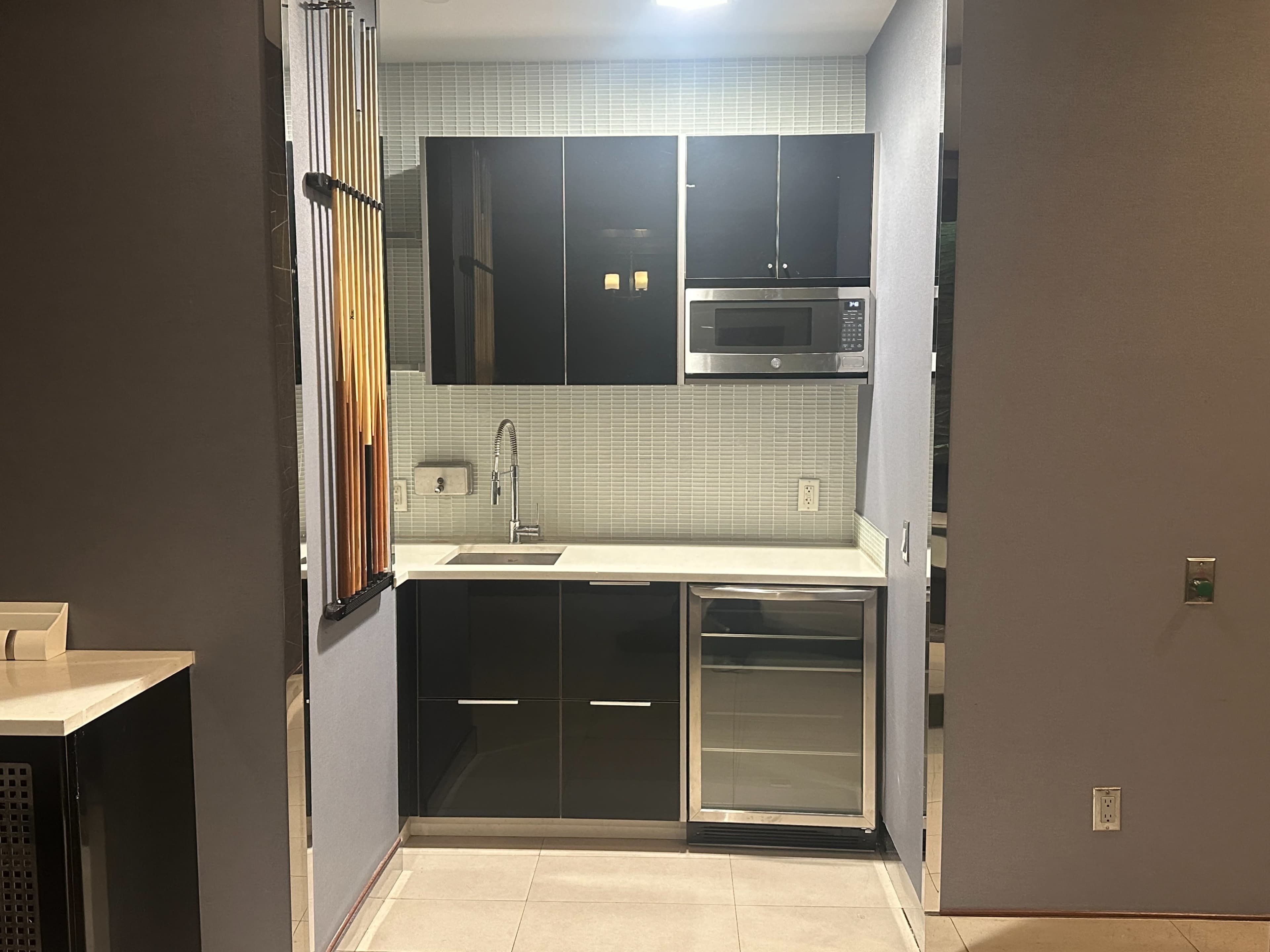 The image shows a modern kitchen with black cabinetry, a microwave, and a stainless steel refrigerator.