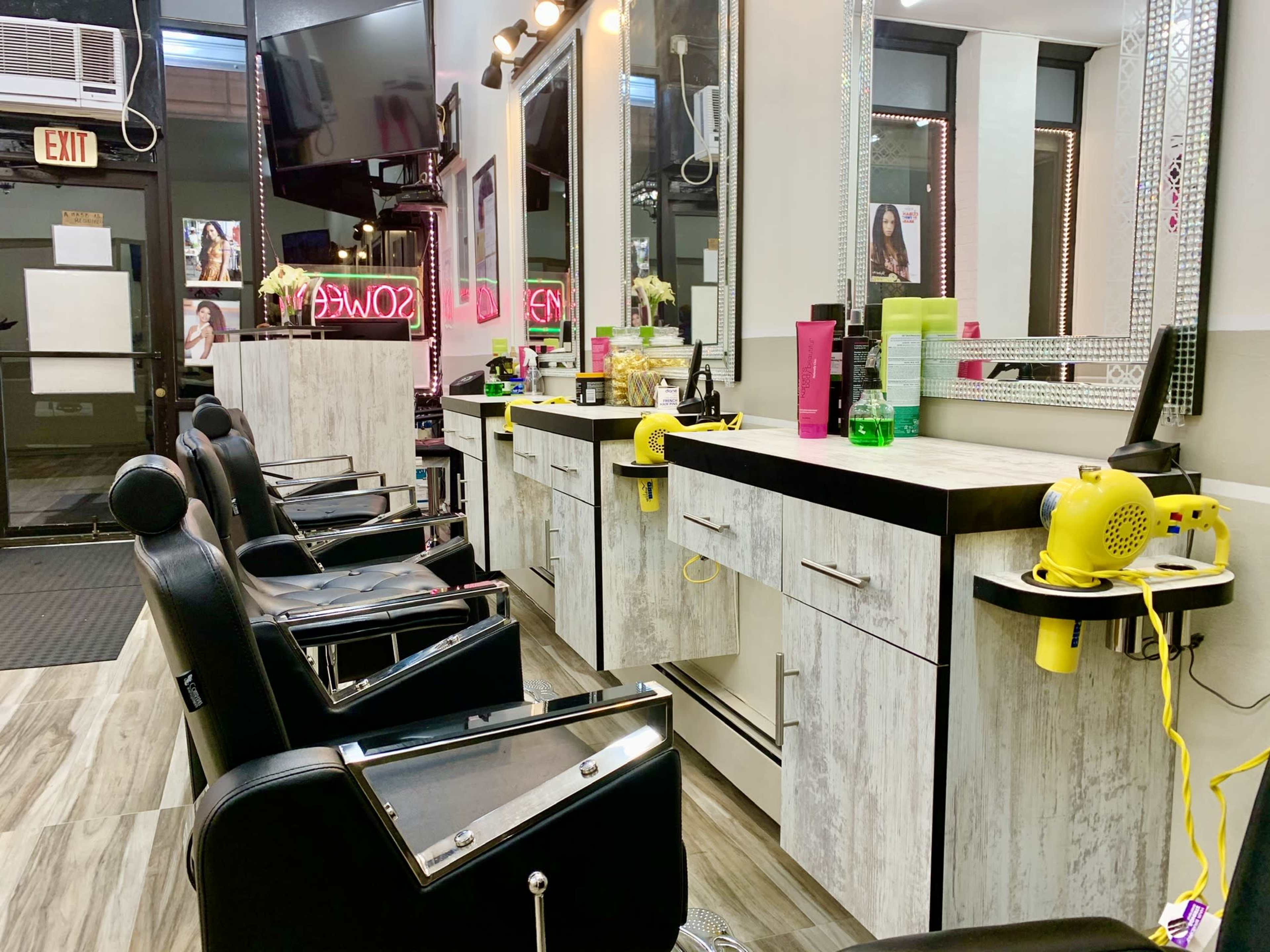 A hair salon interior with several styling chairs, mirrors, and hairdryers placed on a counter.