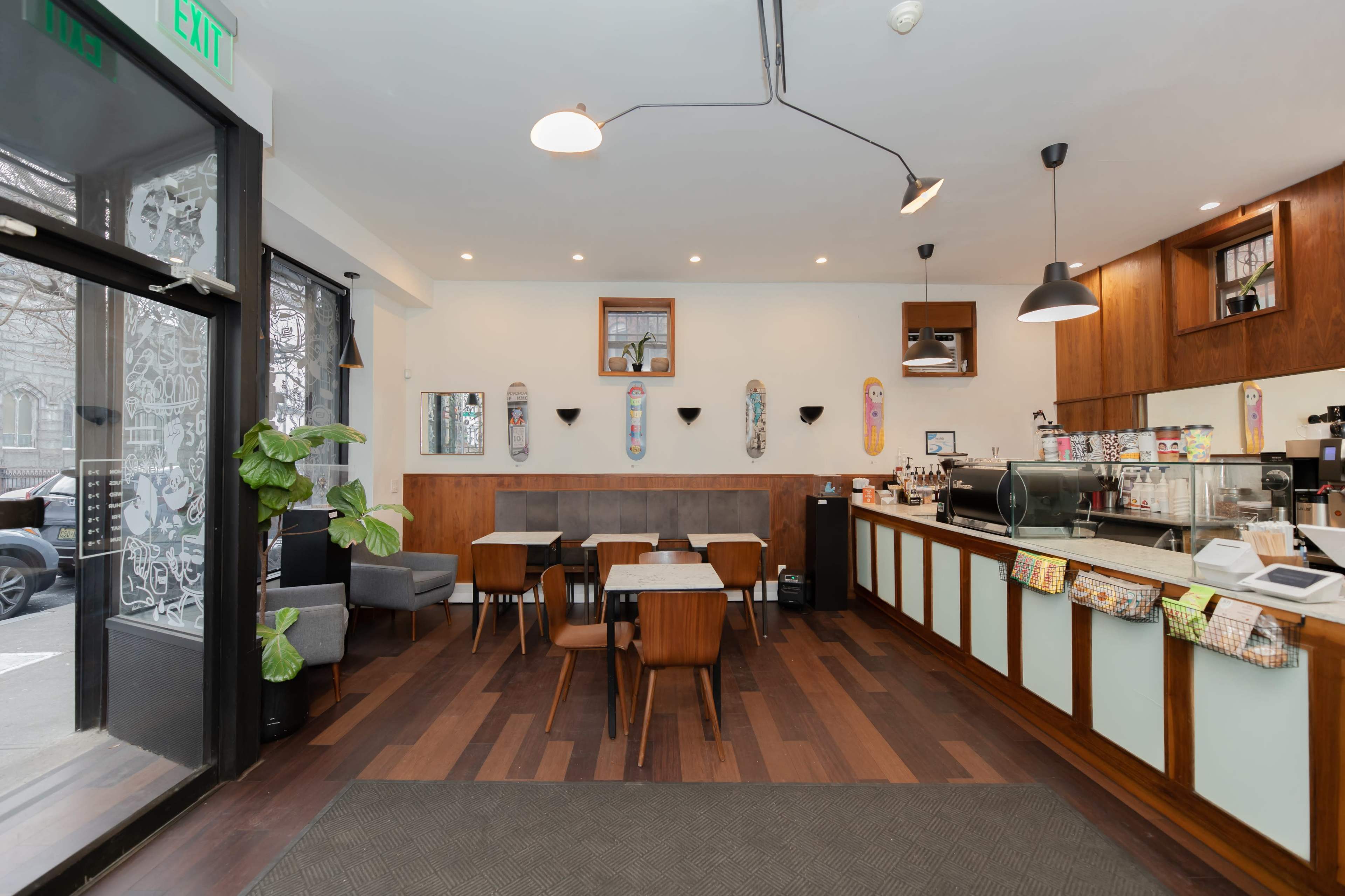 The interior of a café features wooden furniture, a counter with coffee equipment, and skateboard decor on the walls.