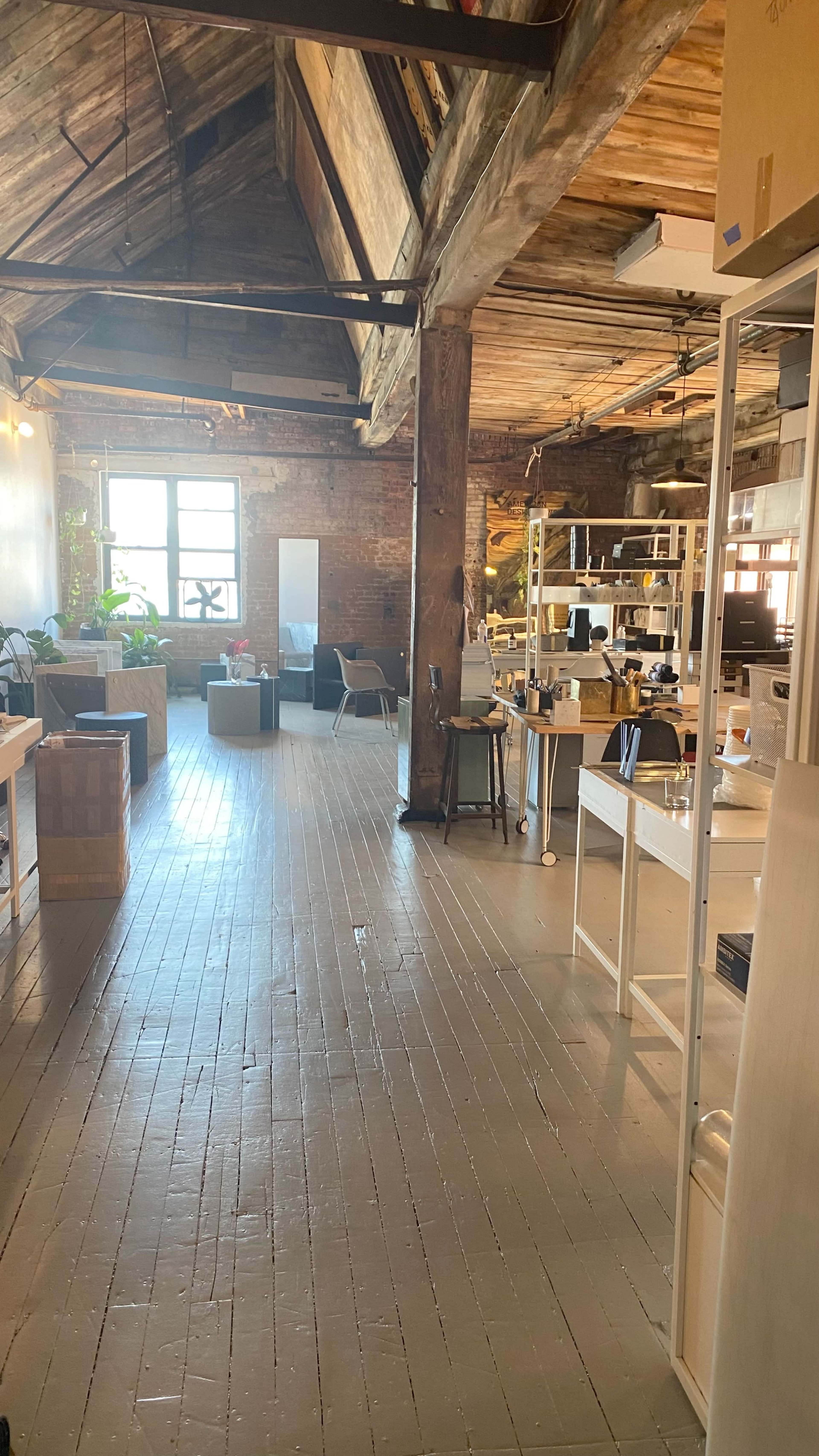 A spacious loft-style office with wooden beams, divided workstations, and various seating areas.
