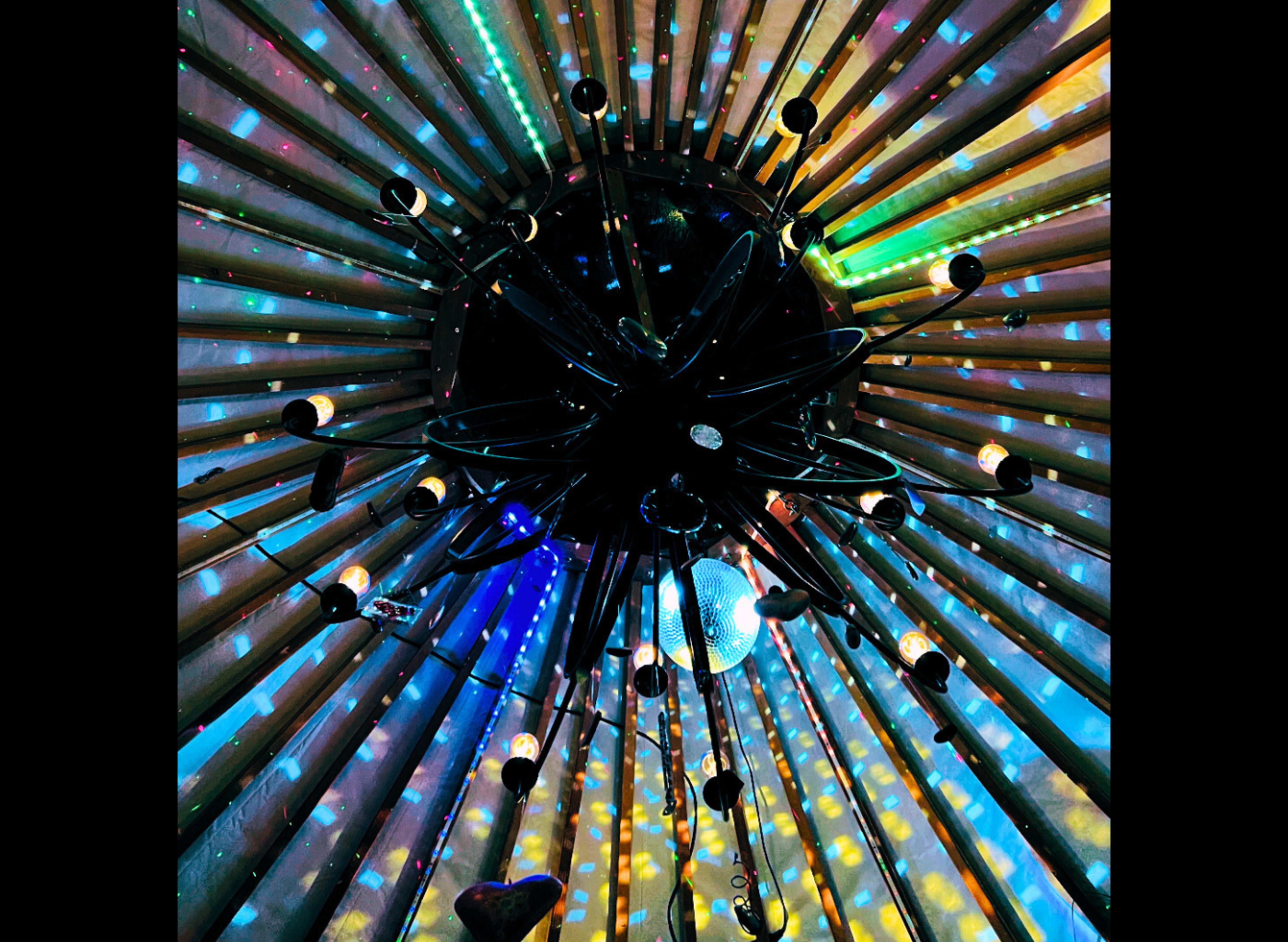 A ceiling fixture with multiple light sources casting colorful reflections on a textured surface.