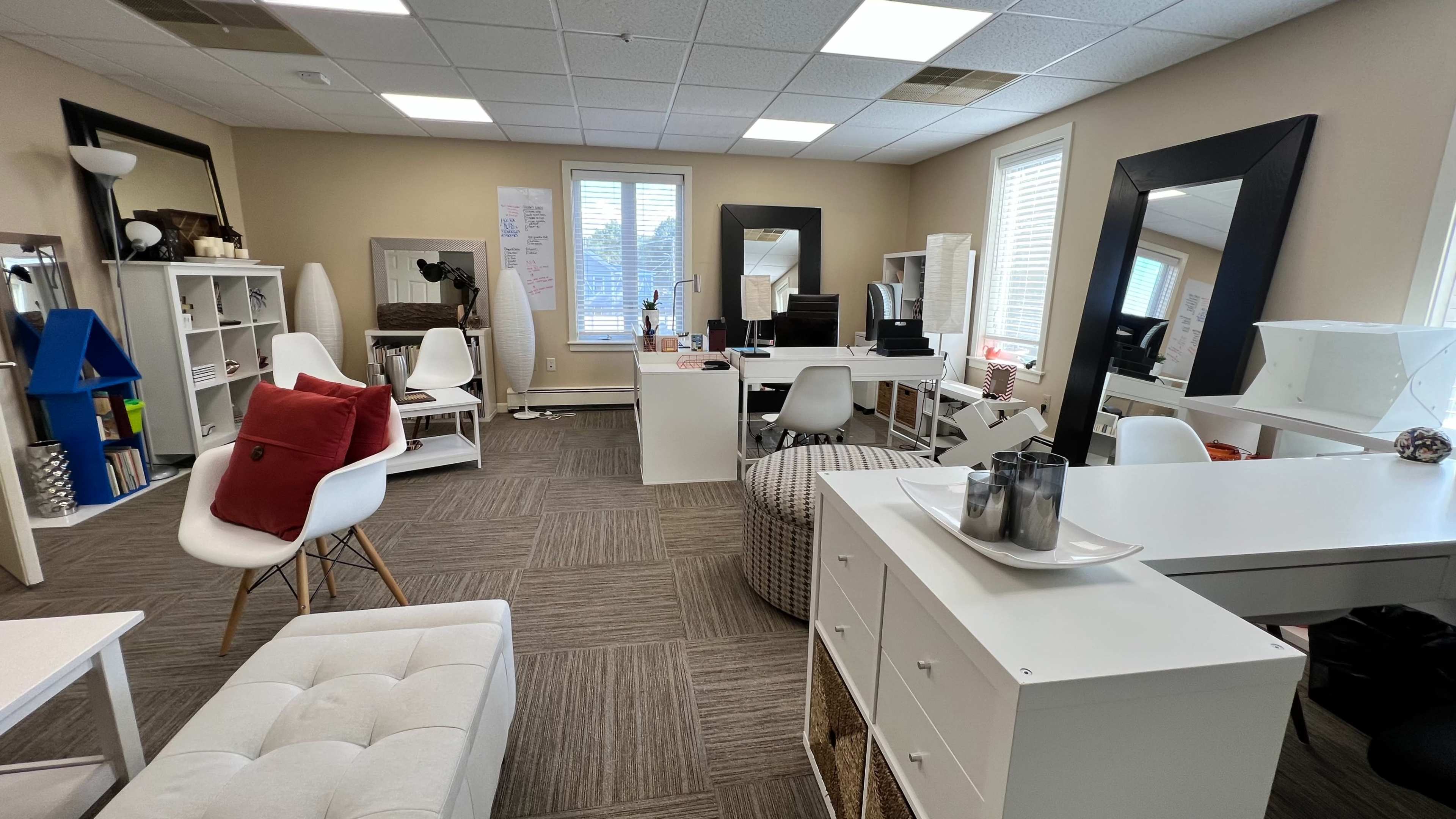 A spacious office featuring multiple workstations arranged around a central area with various seating options and storage units.