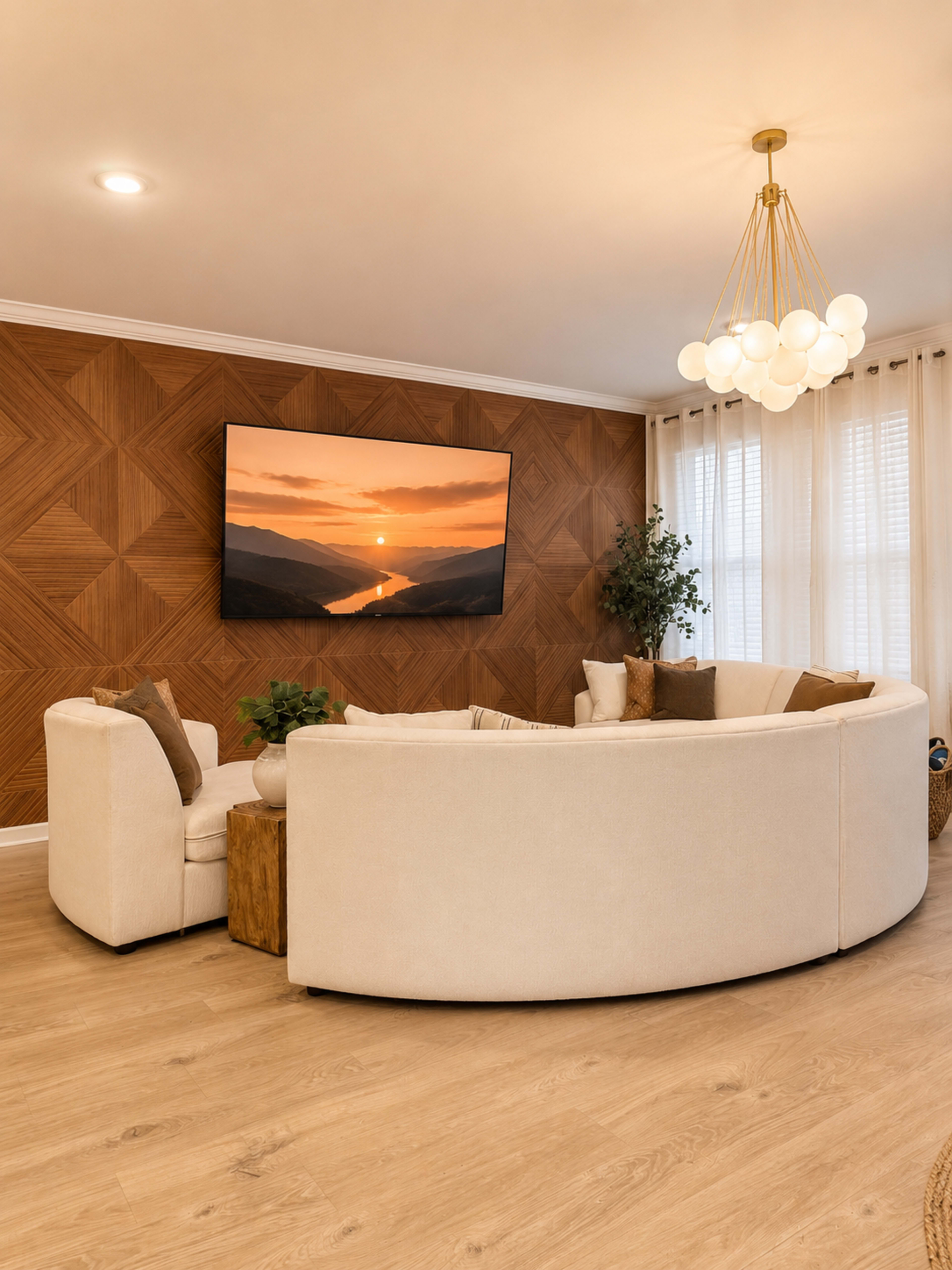The image shows a modern living room with a circular white sofa, a wooden side table, and a large wall-mounted television displaying a scenic sunset, set against a warm, textured wall.