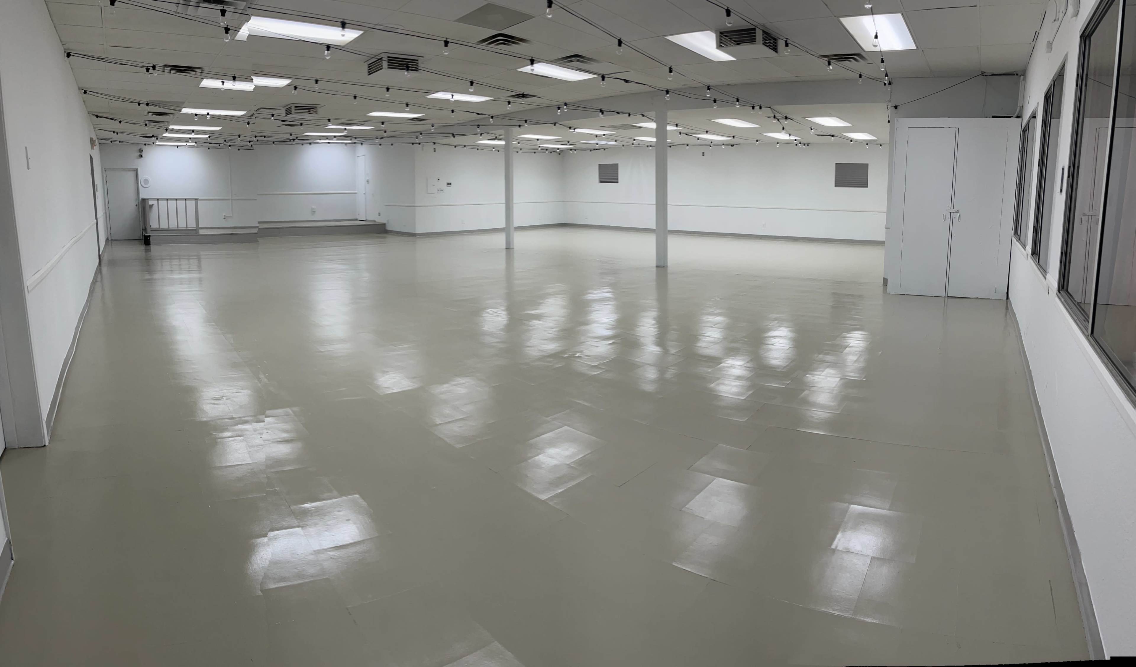 A large, empty indoor space with a smooth, polished floor and overhead fluorescent lighting.