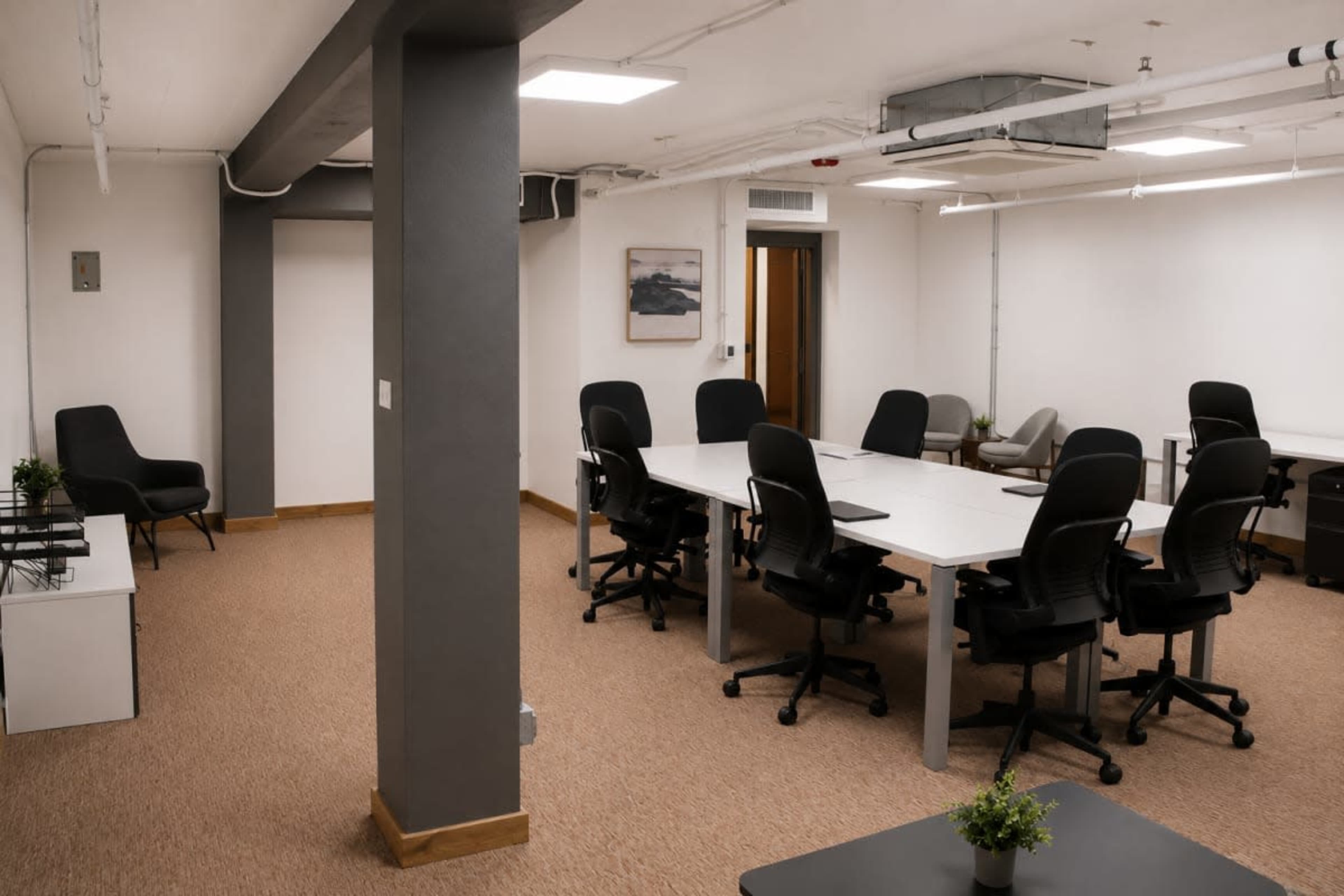 The image shows a well-lit office space with multiple tables and chairs organized for meetings, featuring a neutral color palette and minimalistic decor.
