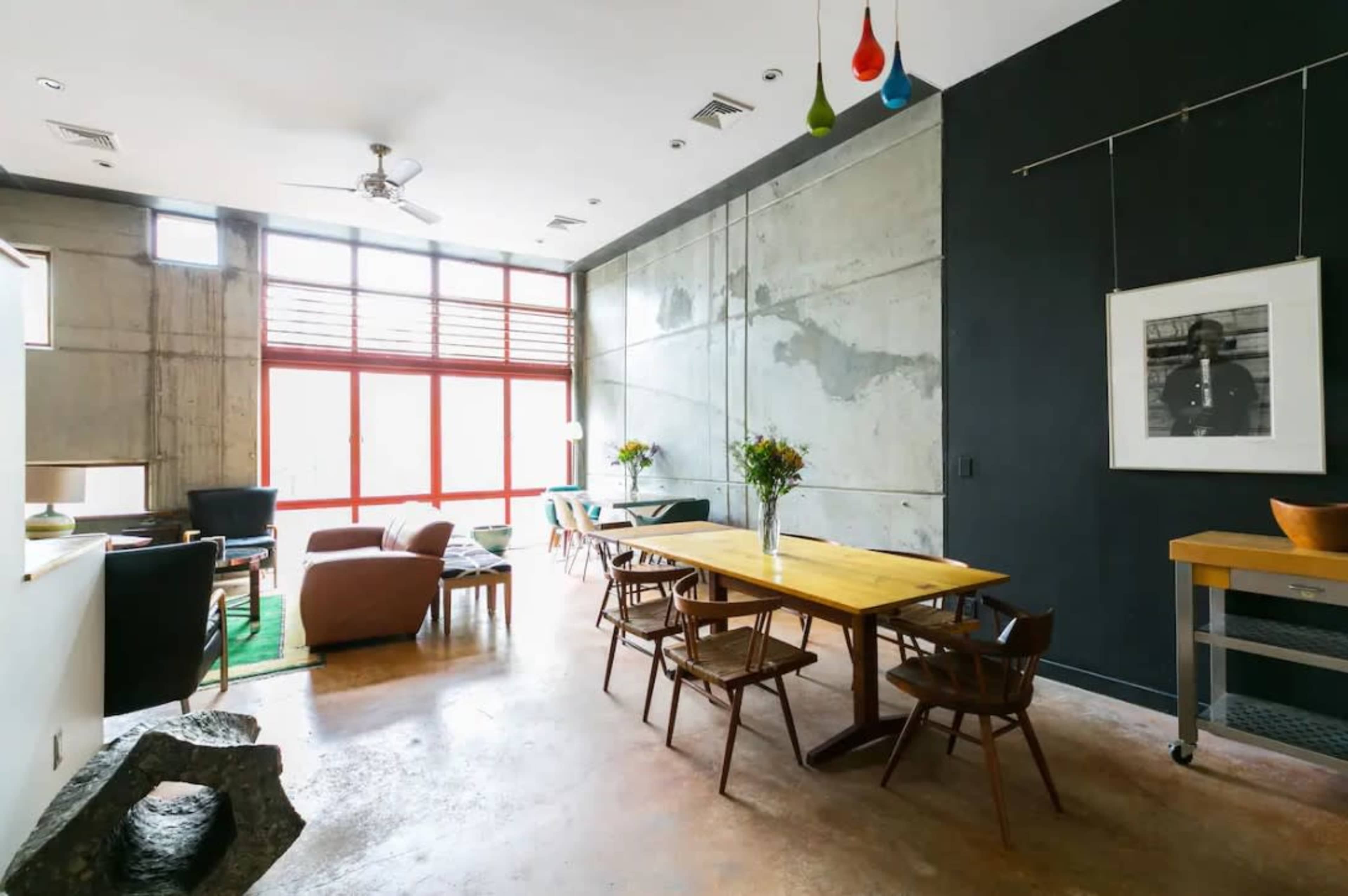 A modern interior space featuring a dining table, chairs, and large windows that allow natural light to fill the room.