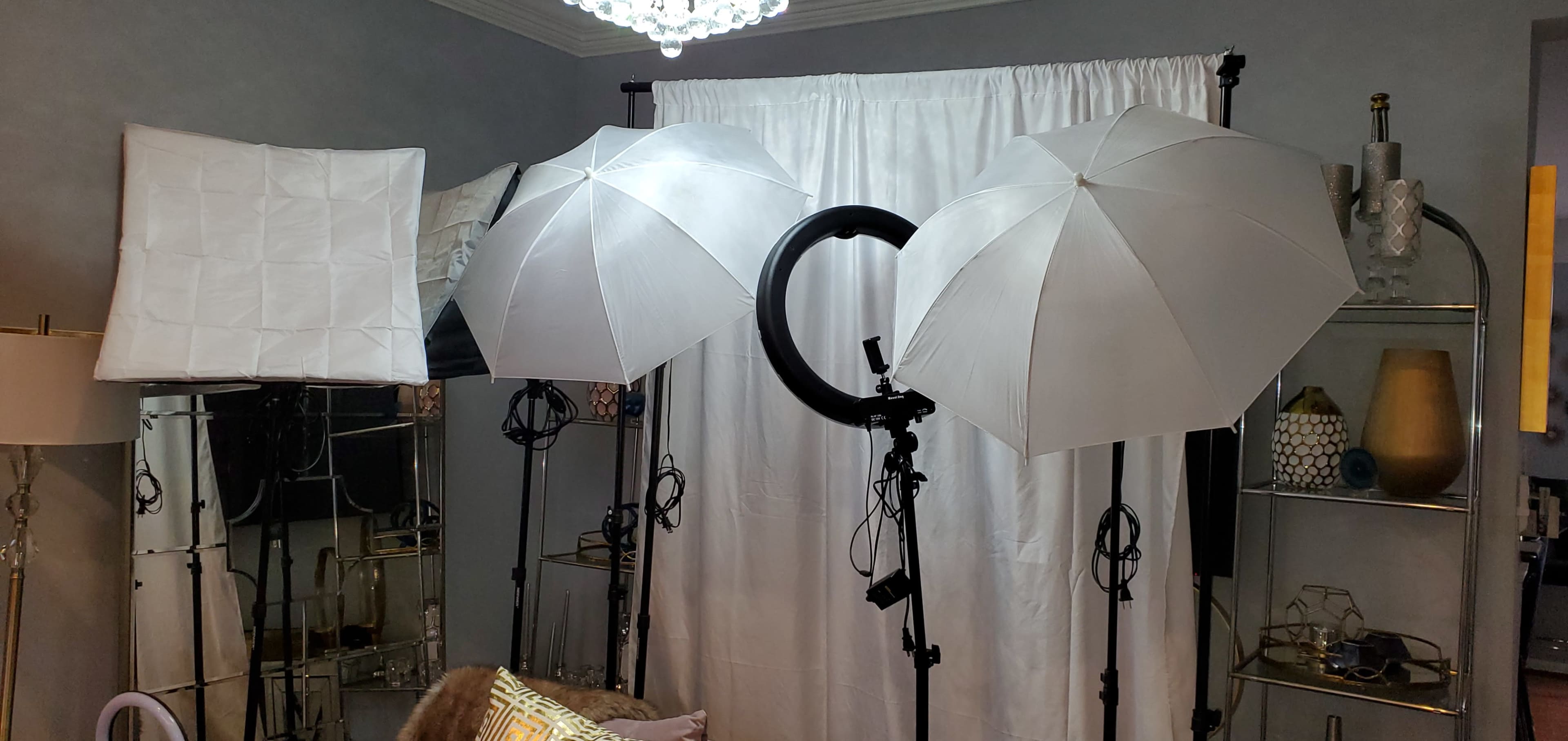 The image shows three photography lighting setups, including softboxes and a ring light, positioned in front of a white backdrop in a room.
