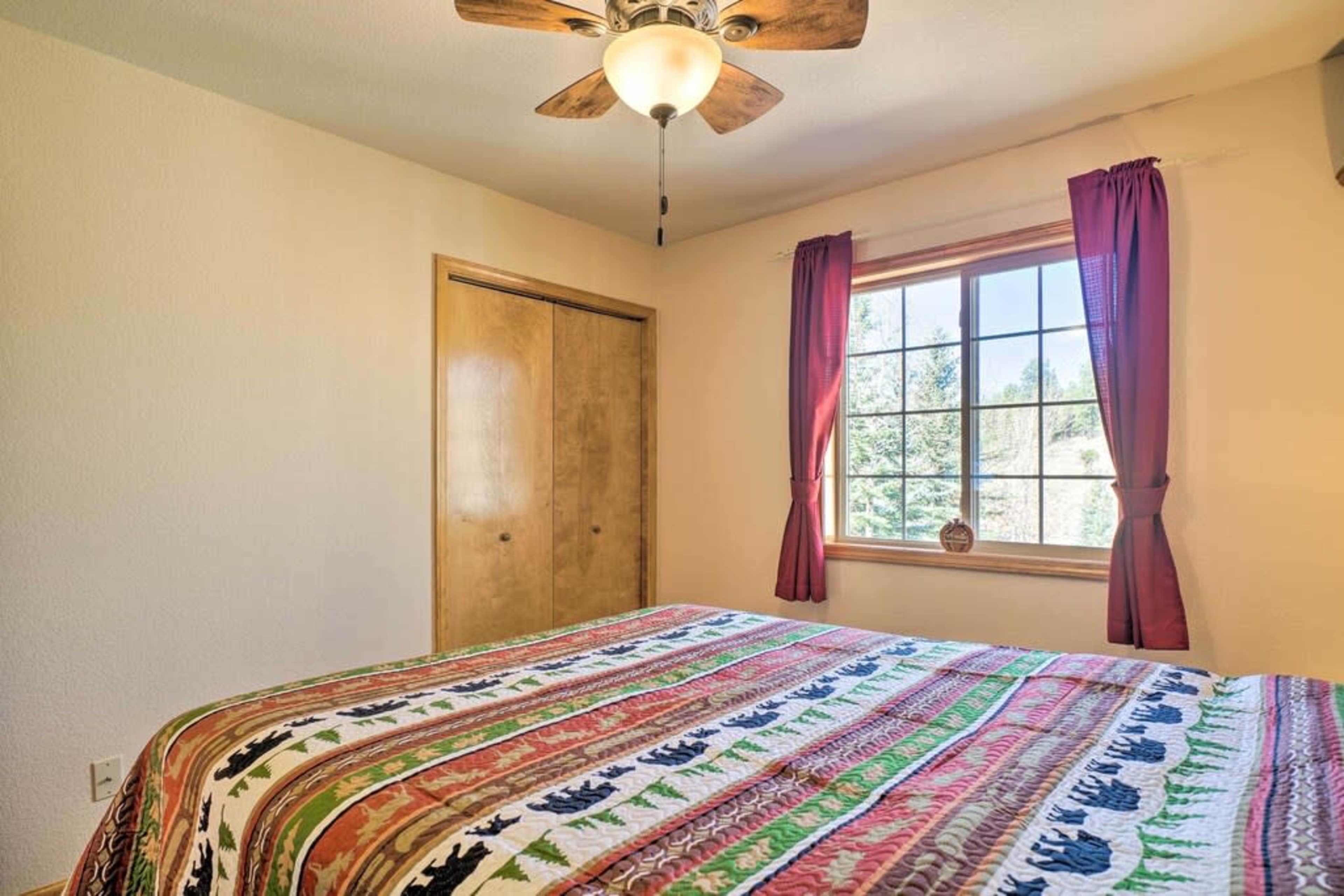 The image shows a bedroom with a patterned bedspread, a window with purple curtains, and a door in the background.