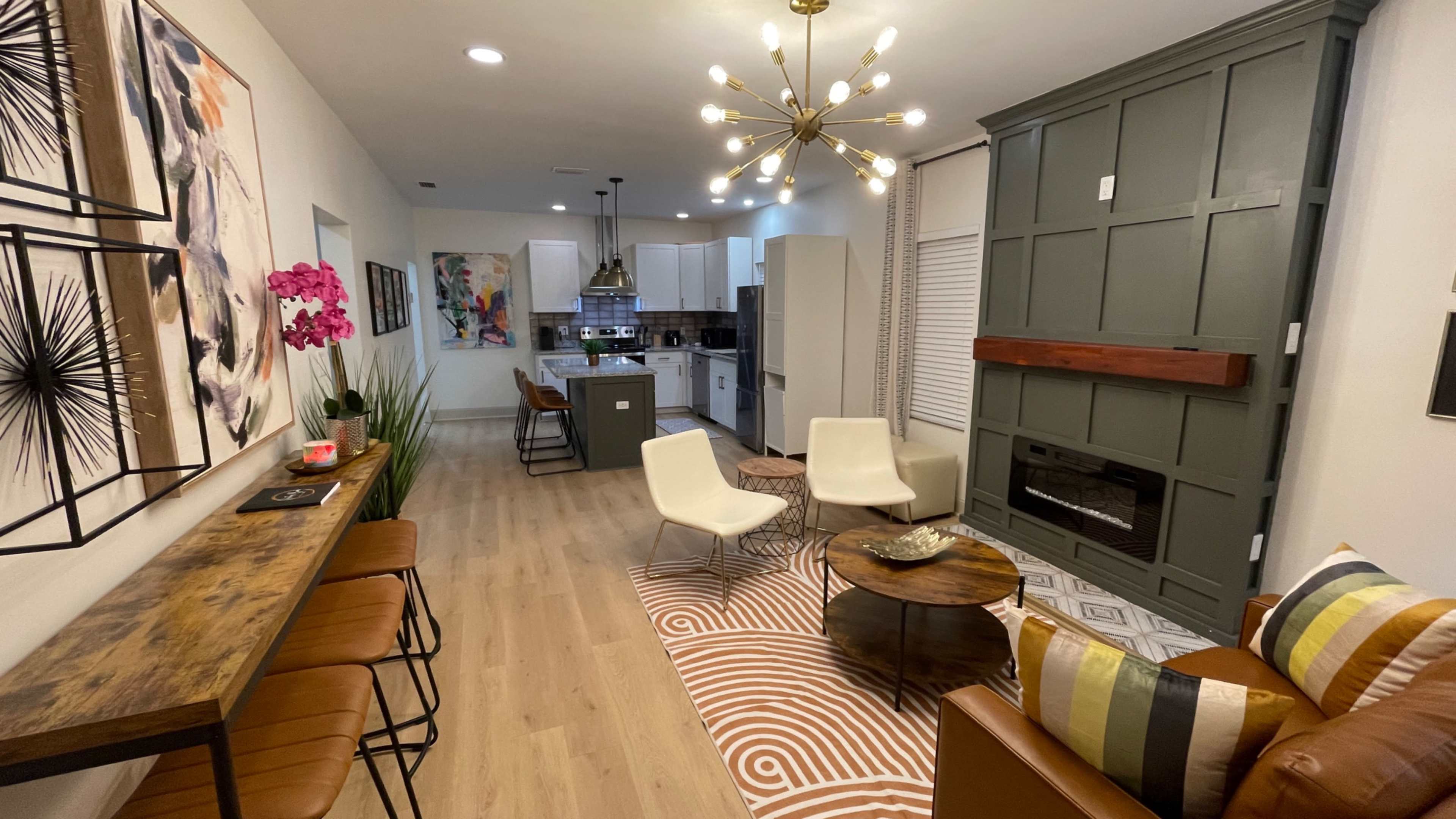A modern living space with a kitchen area, seating furniture, a coffee table, and decorative wall art.