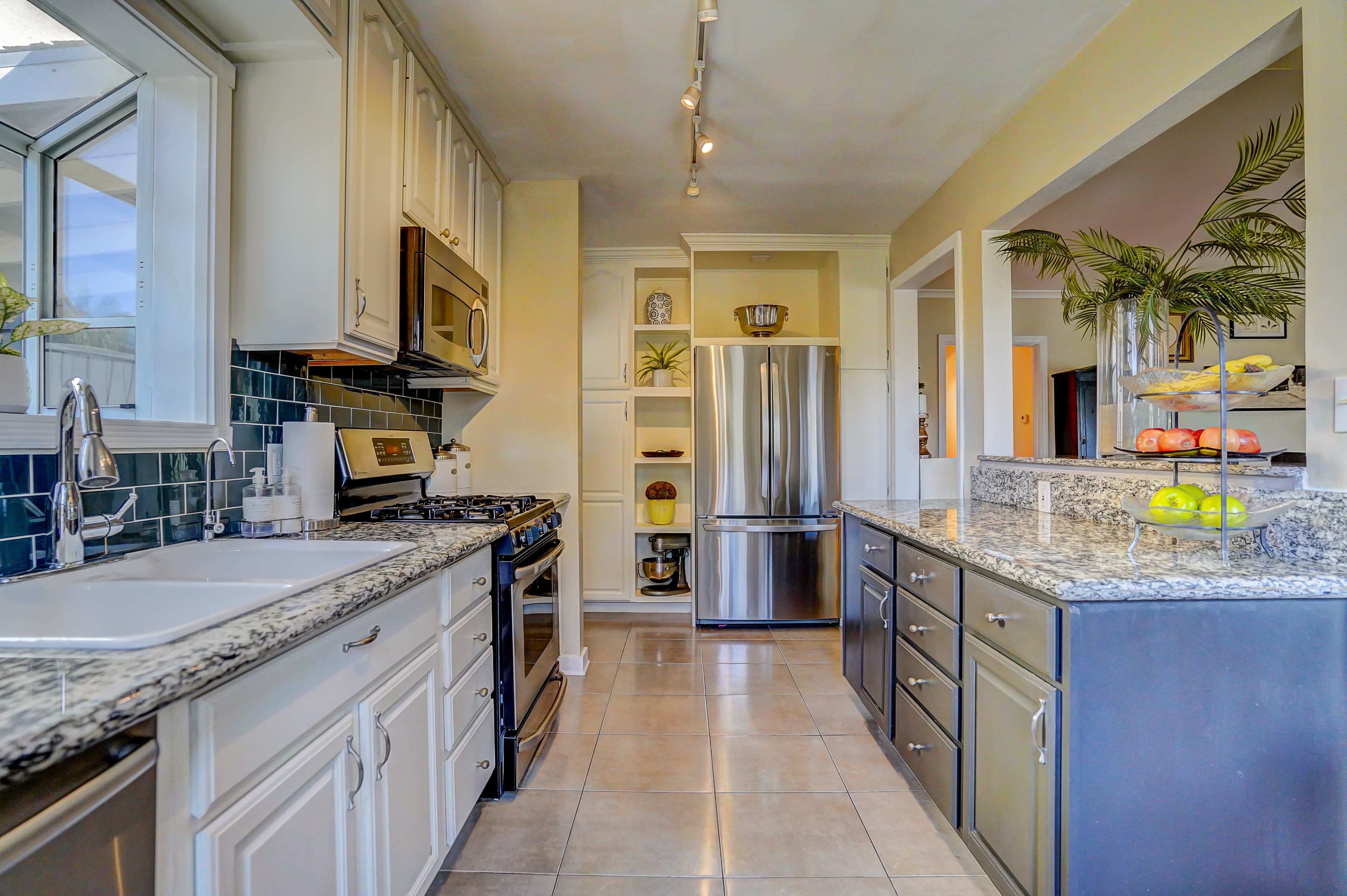 The image shows a modern kitchen featuring stainless steel appliances, granite countertops, and light-colored cabinetry.