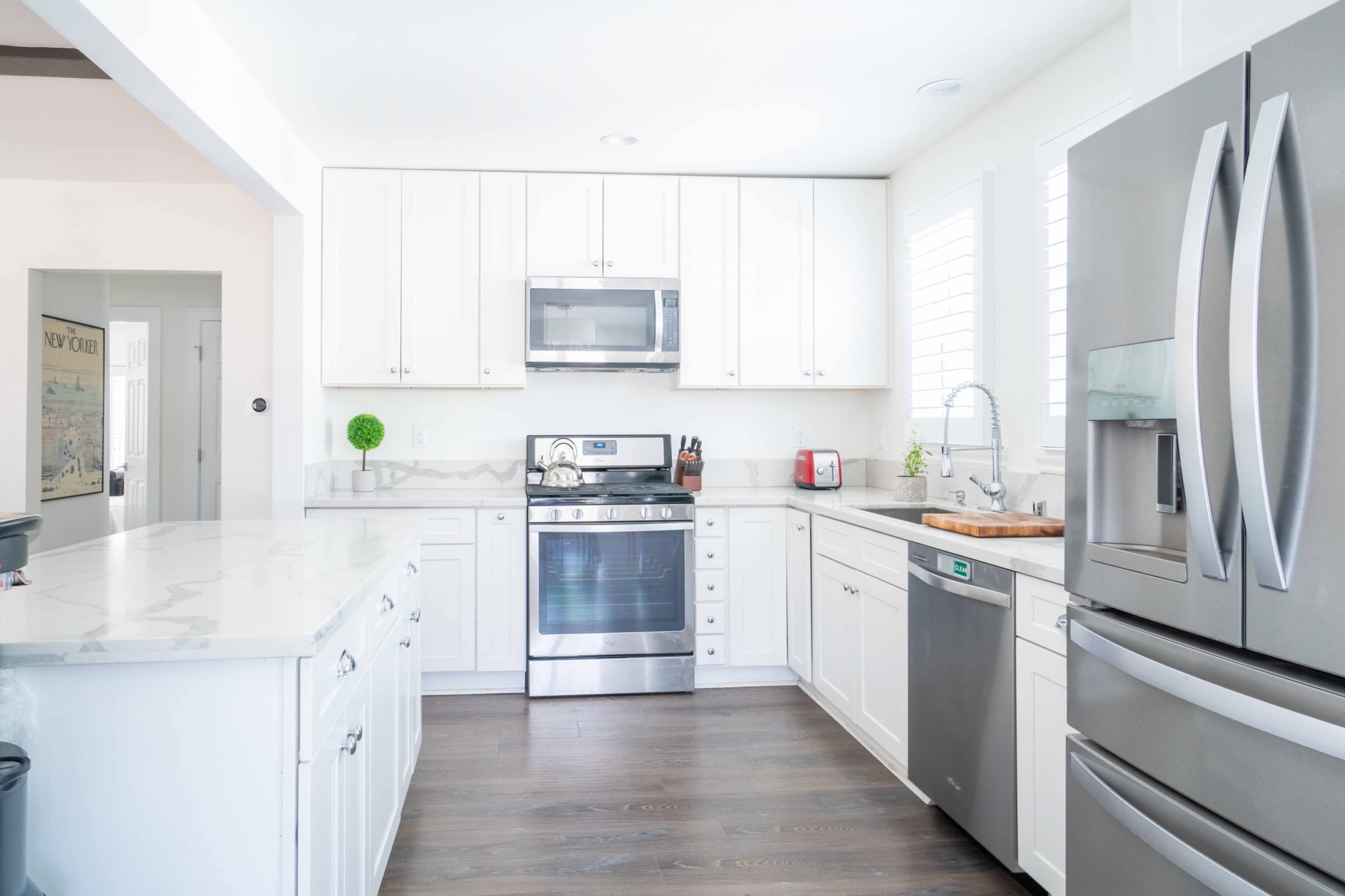 A modern kitchen with white cabinetry, stainless steel appliances, and a large island with a countertop.