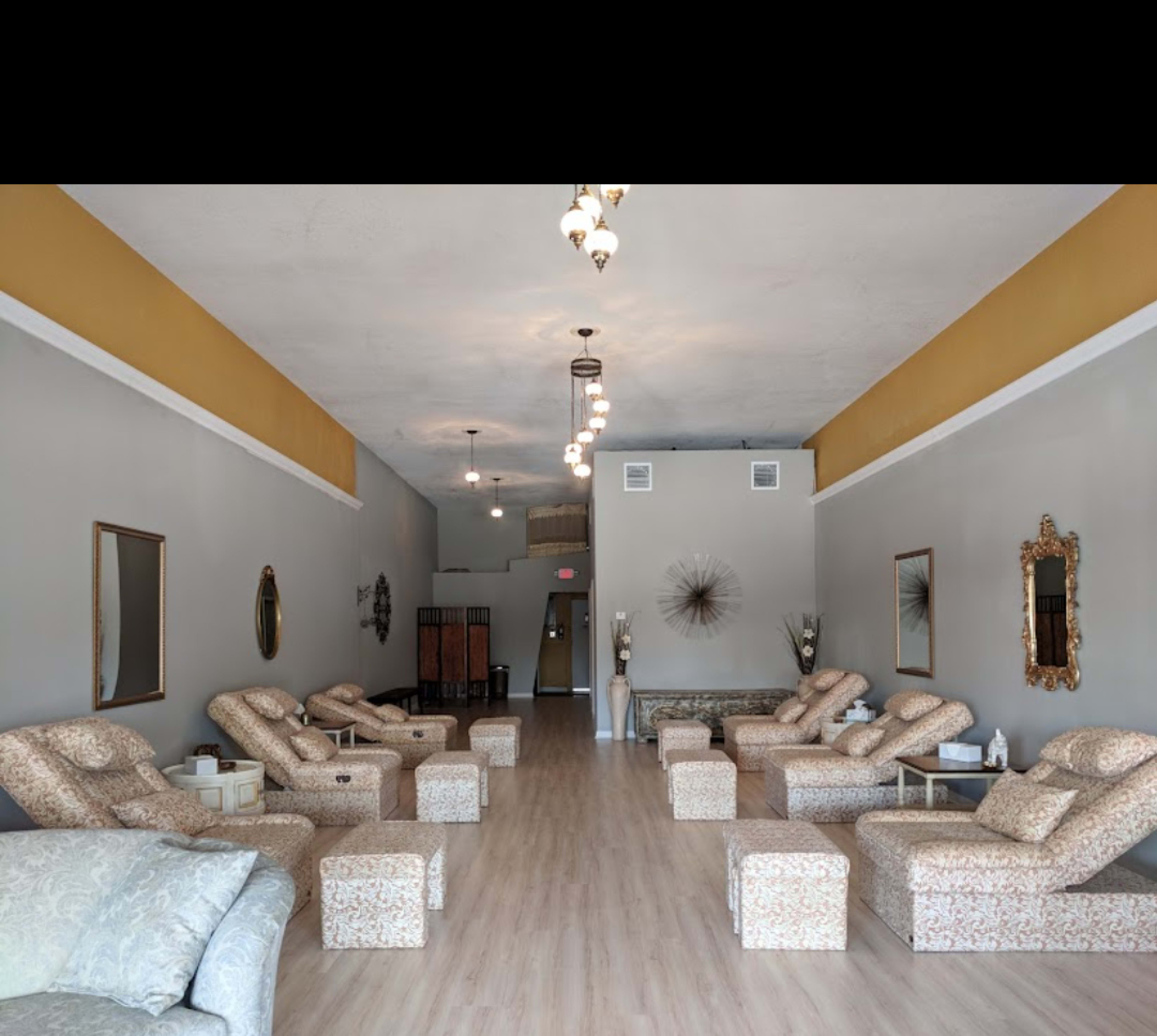 A spacious salon with multiple reclining chairs arranged in a row along the walls, and decorative mirrors and accents enhancing the interior.