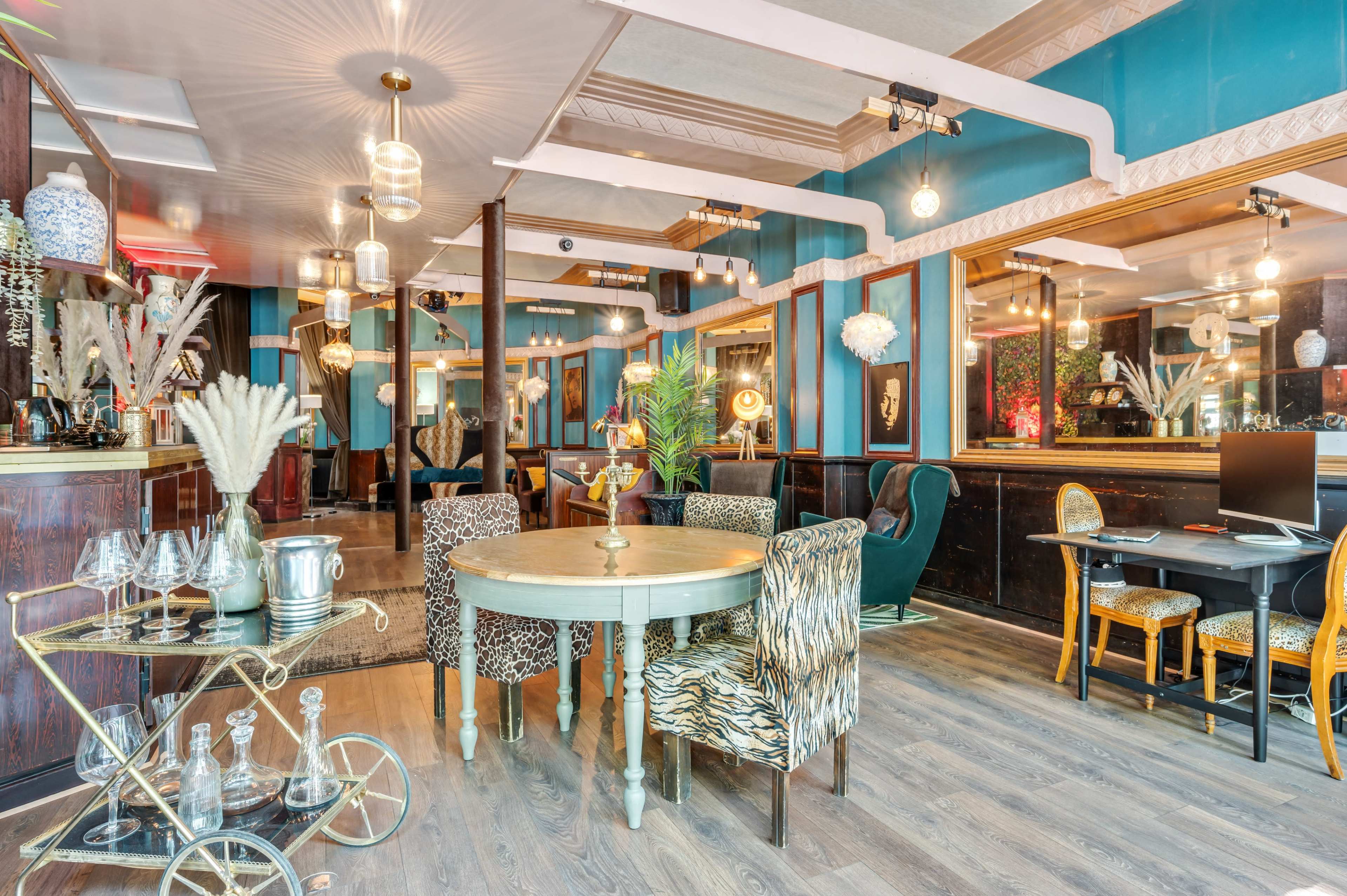 A stylized interior of a restaurant featuring a circular table, patterned chairs, and a decorative bar with various glassware.
