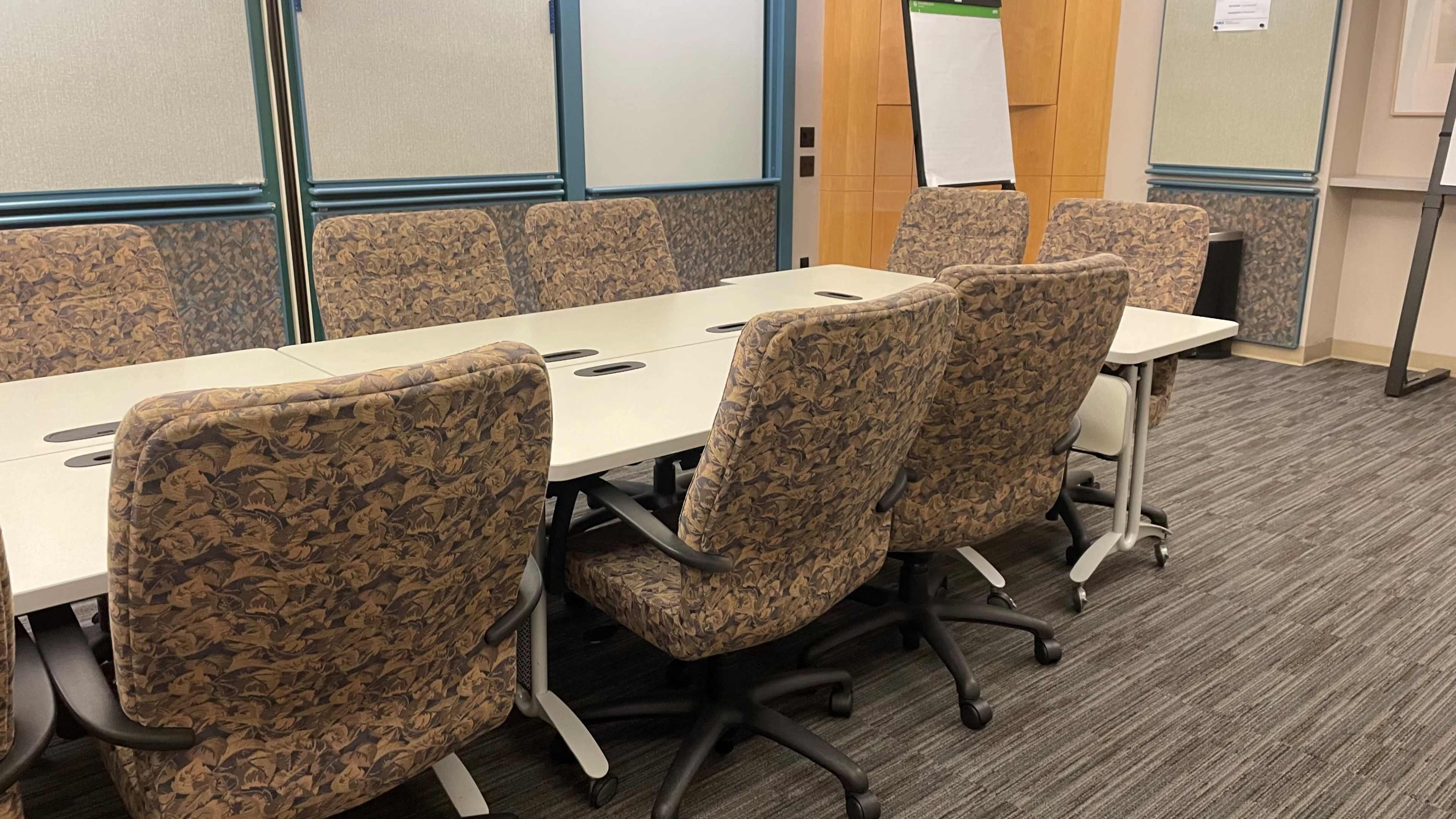 A conference room features a rectangular table surrounded by several office chairs.