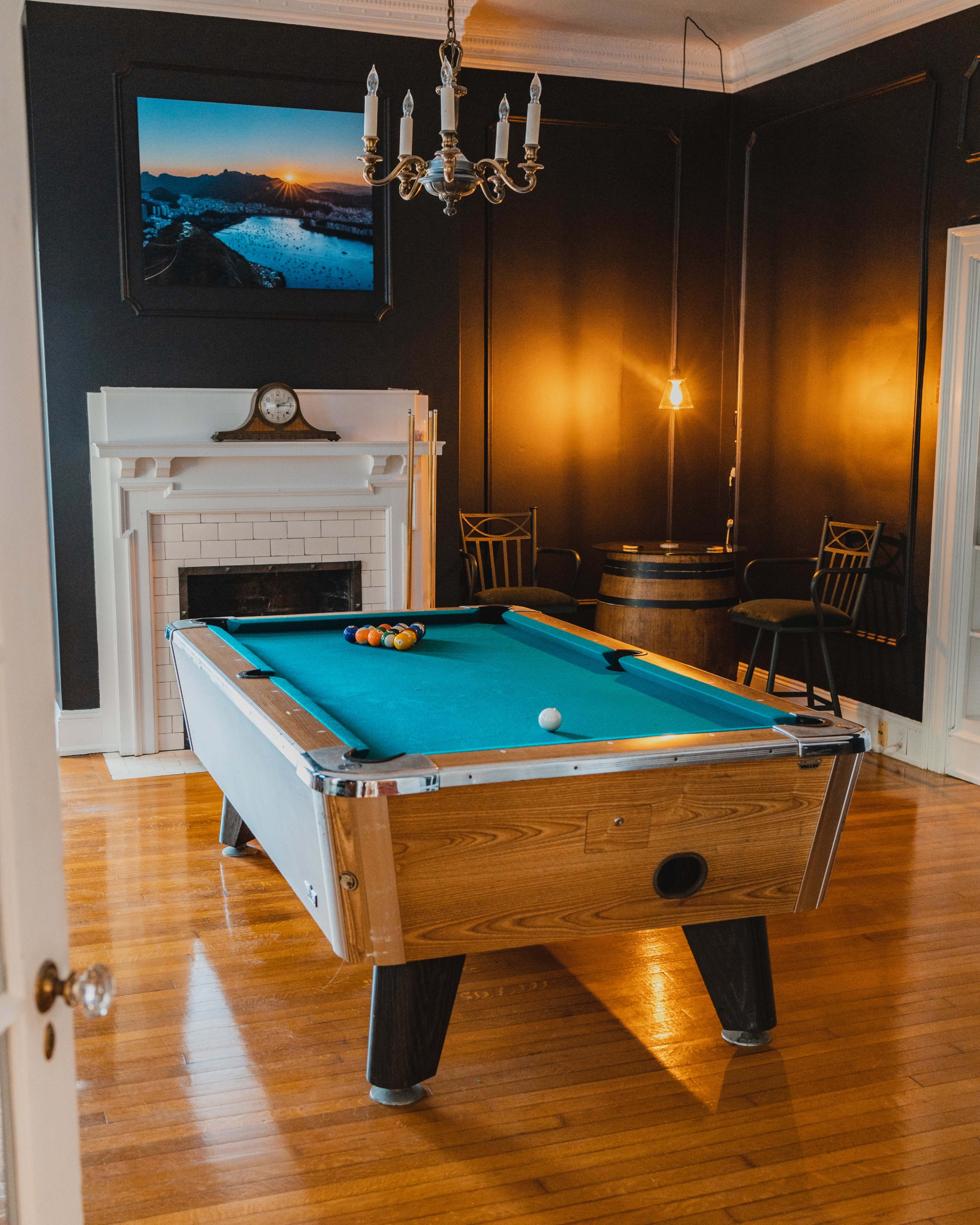 A billiard room featuring a pool table, a fireplace, a chandelier, and a large framed photo on the wall.