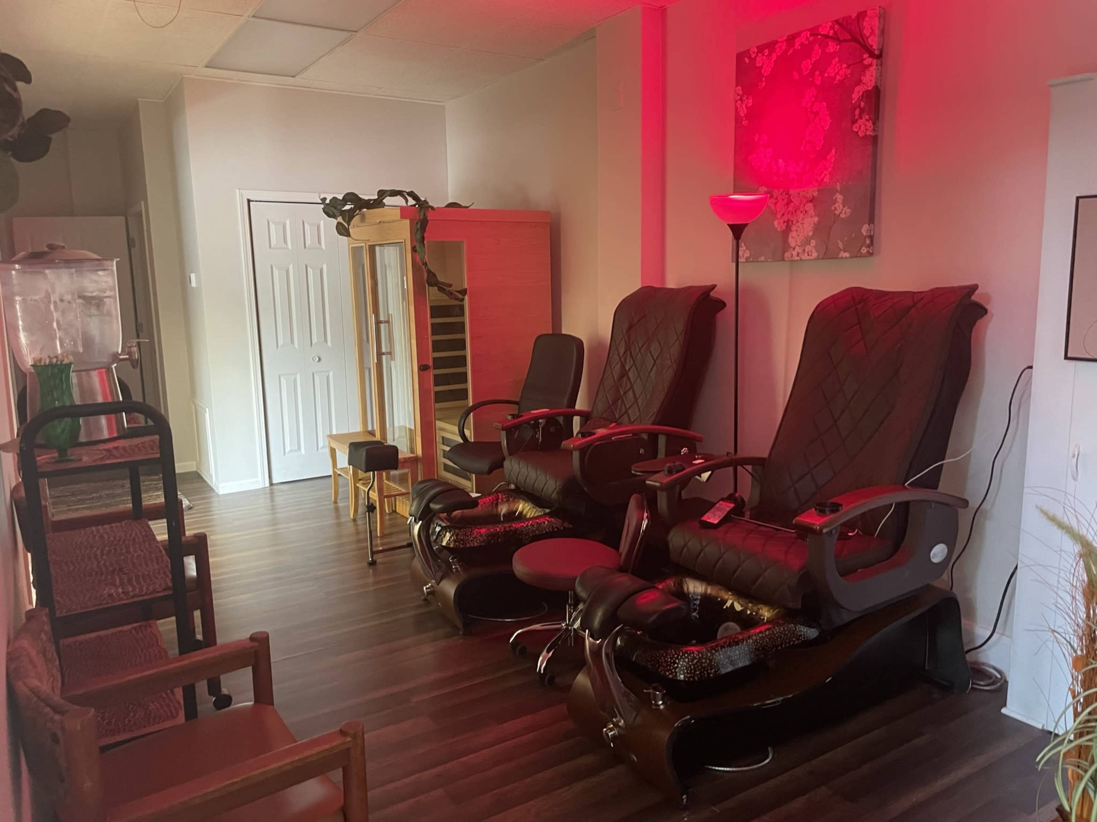 A spa area with two large massage chairs, a decorative lamp, and wooden furnishings arranged along a wall.