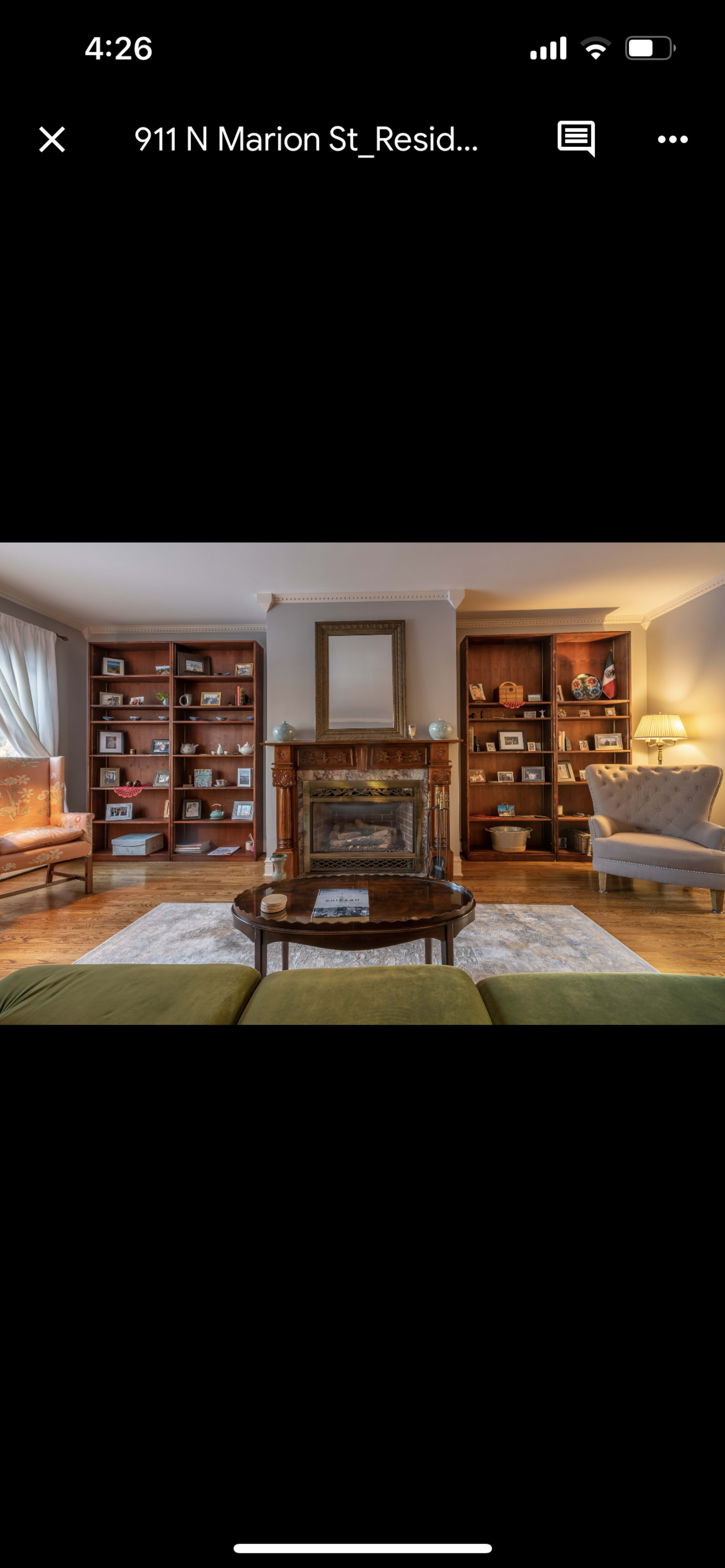 A living room with a central coffee table, a fireplace, and bookcases filled with framed photos and decorative items.