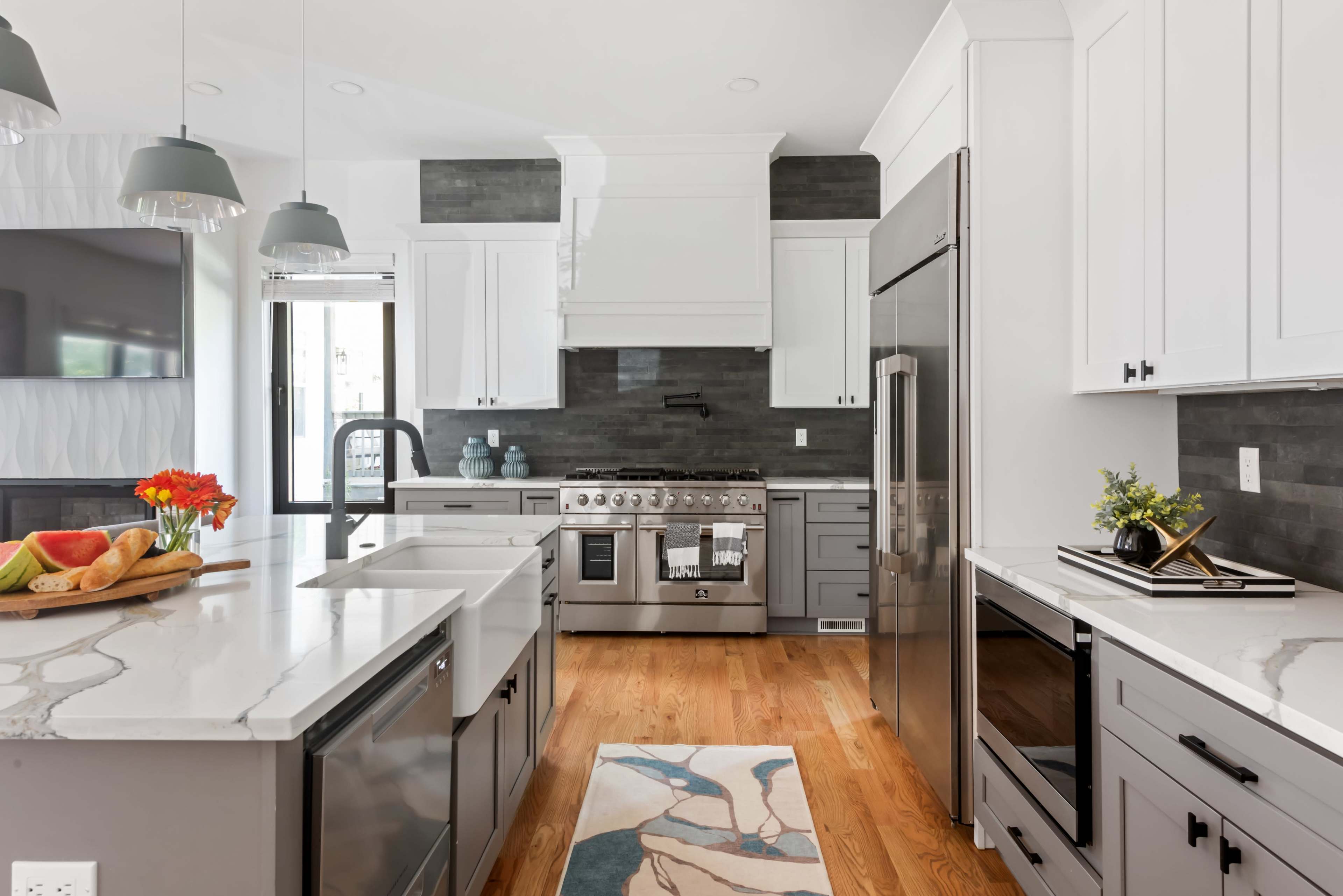 The kitchen features modern gray cabinets, a stainless steel stove, and a spacious island with