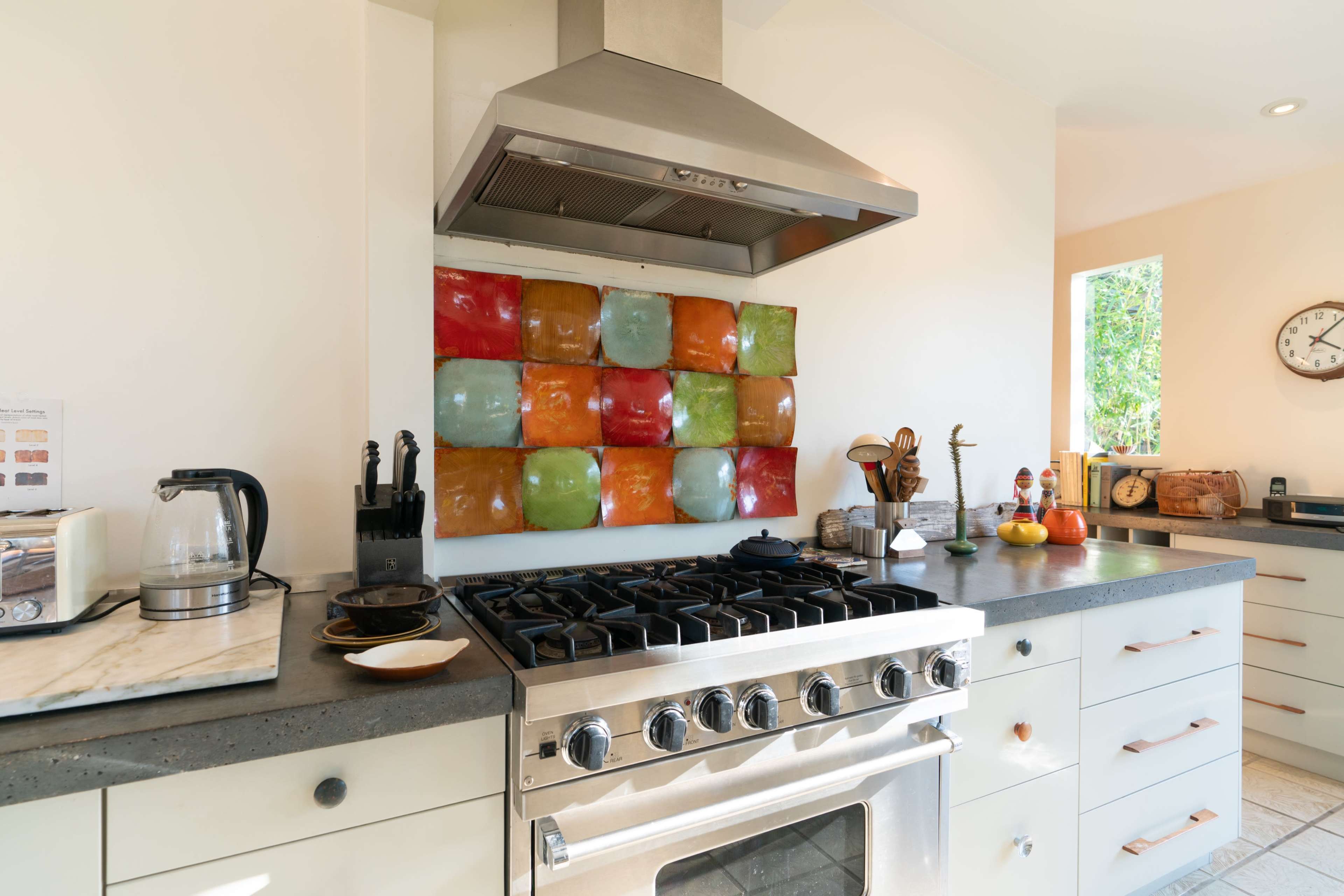 The kitchen features a stainless steel stove and a colorful tiled backsplash with a modern design.