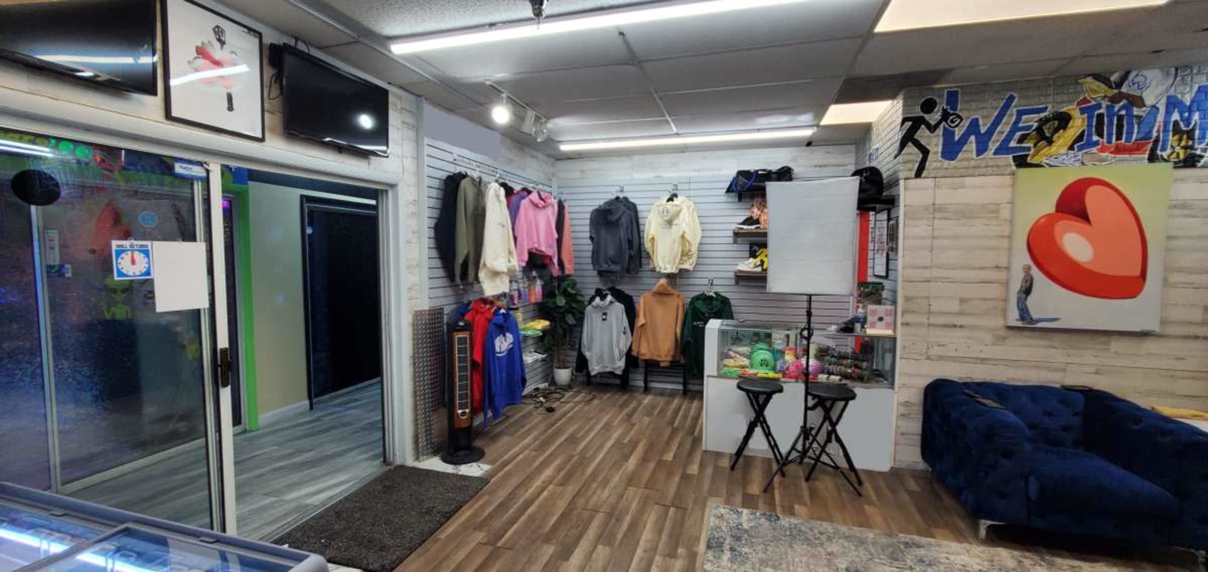 The image shows an interior of a retail store featuring clothing displays, sports memorabilia, and a seating area.