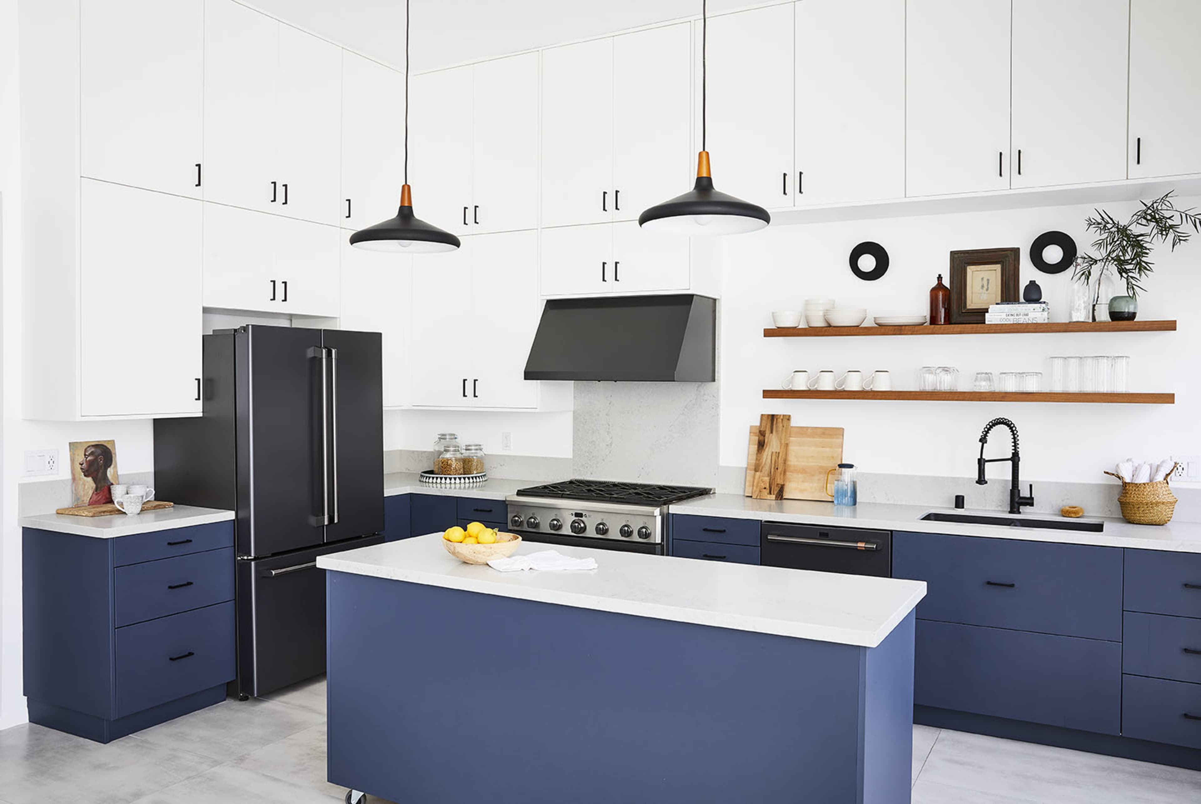 A modern kitchen with black and white cabinetry, a large island with a blue base, and stainless steel appliances.
