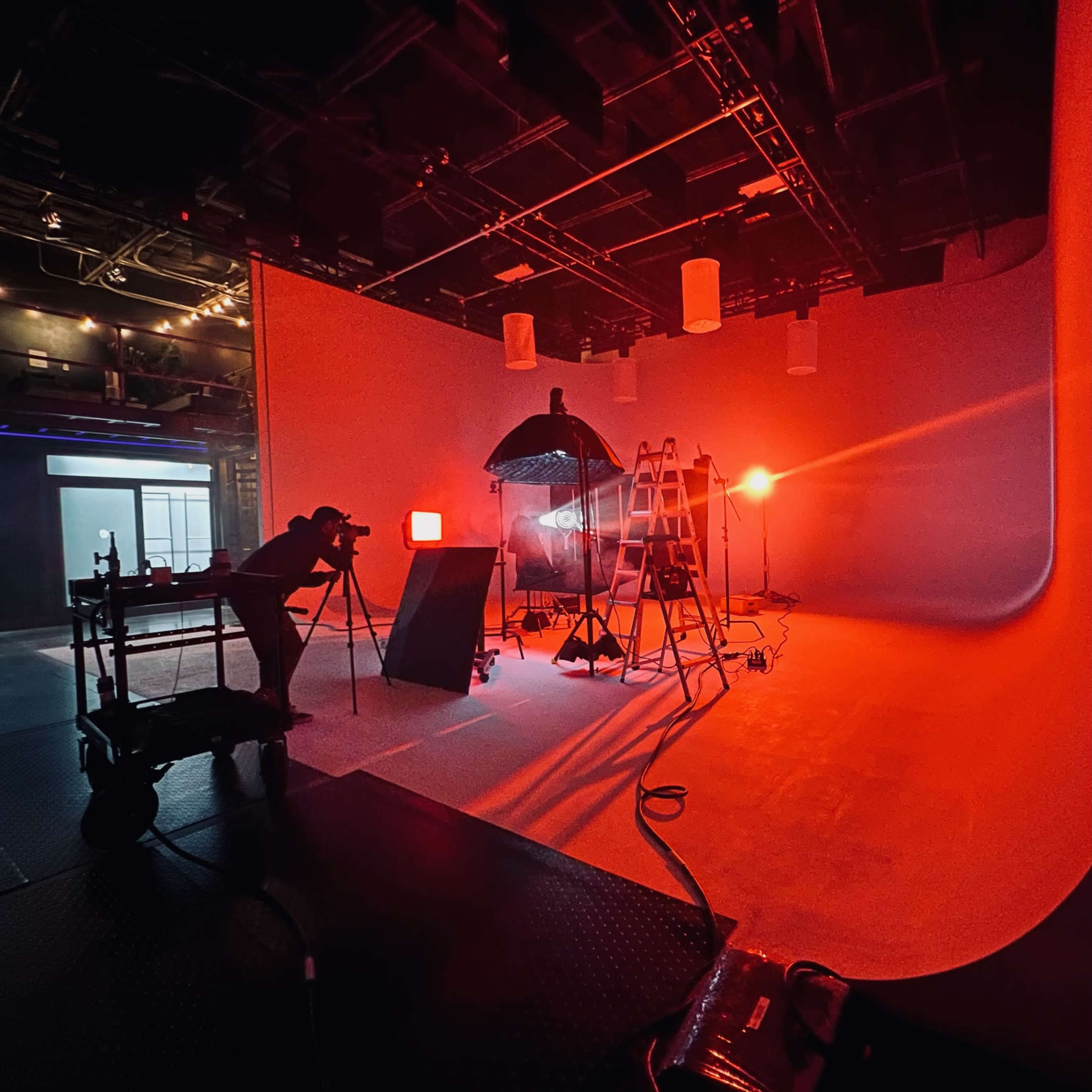 A photography studio is set up with various lighting equipment, a backdrop, and a photographer capturing an image.