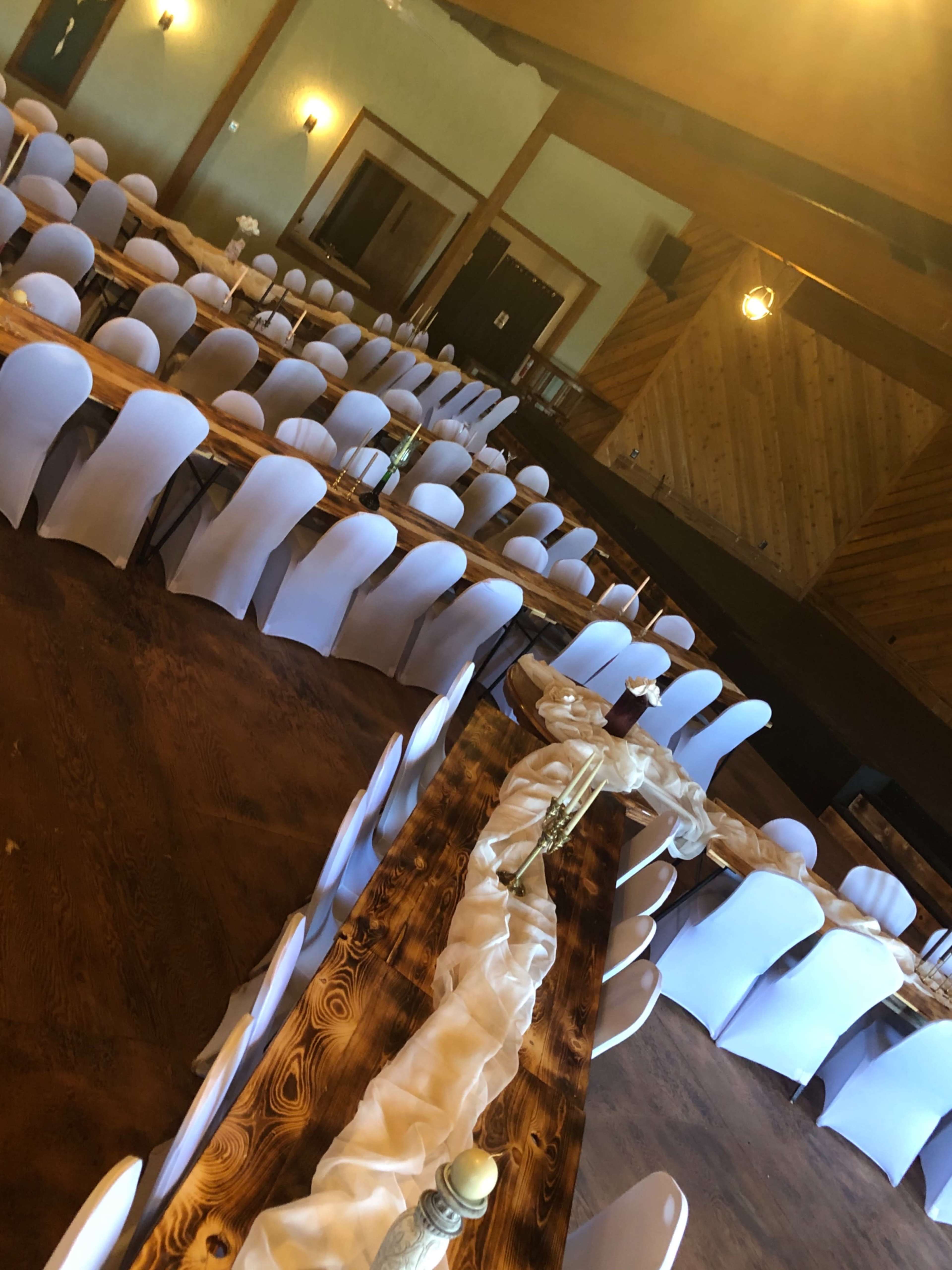 A banquet hall set up with rows of tables covered in white linens and surrounded by white chairs.