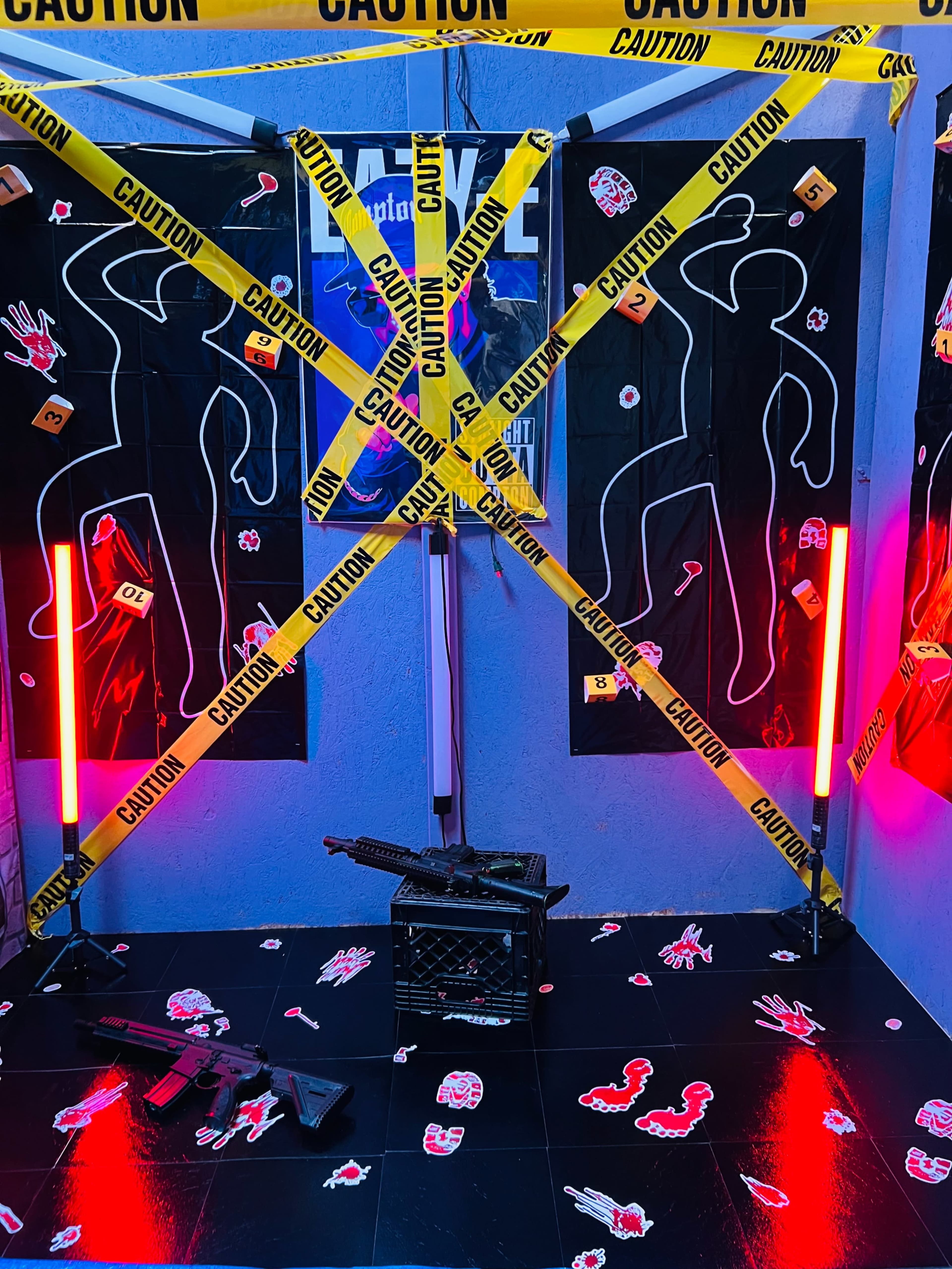 The image shows a room decorated with caution tape, crime scene outlines, and scattered accessories, creating a suspenseful atmosphere.