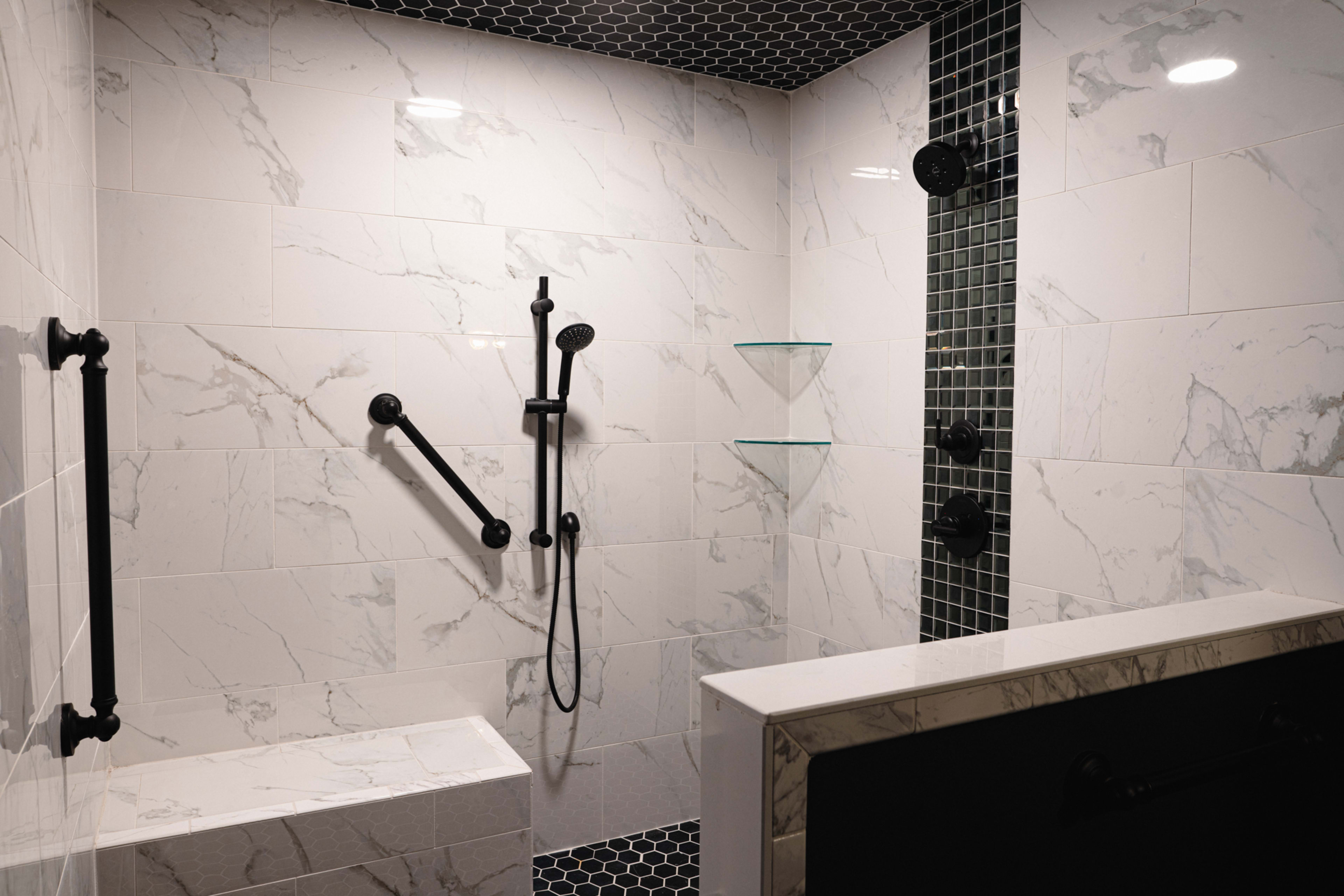 The image shows a modern shower enclosure featuring white marble tiles, black shower fixtures, and built-in shelving.