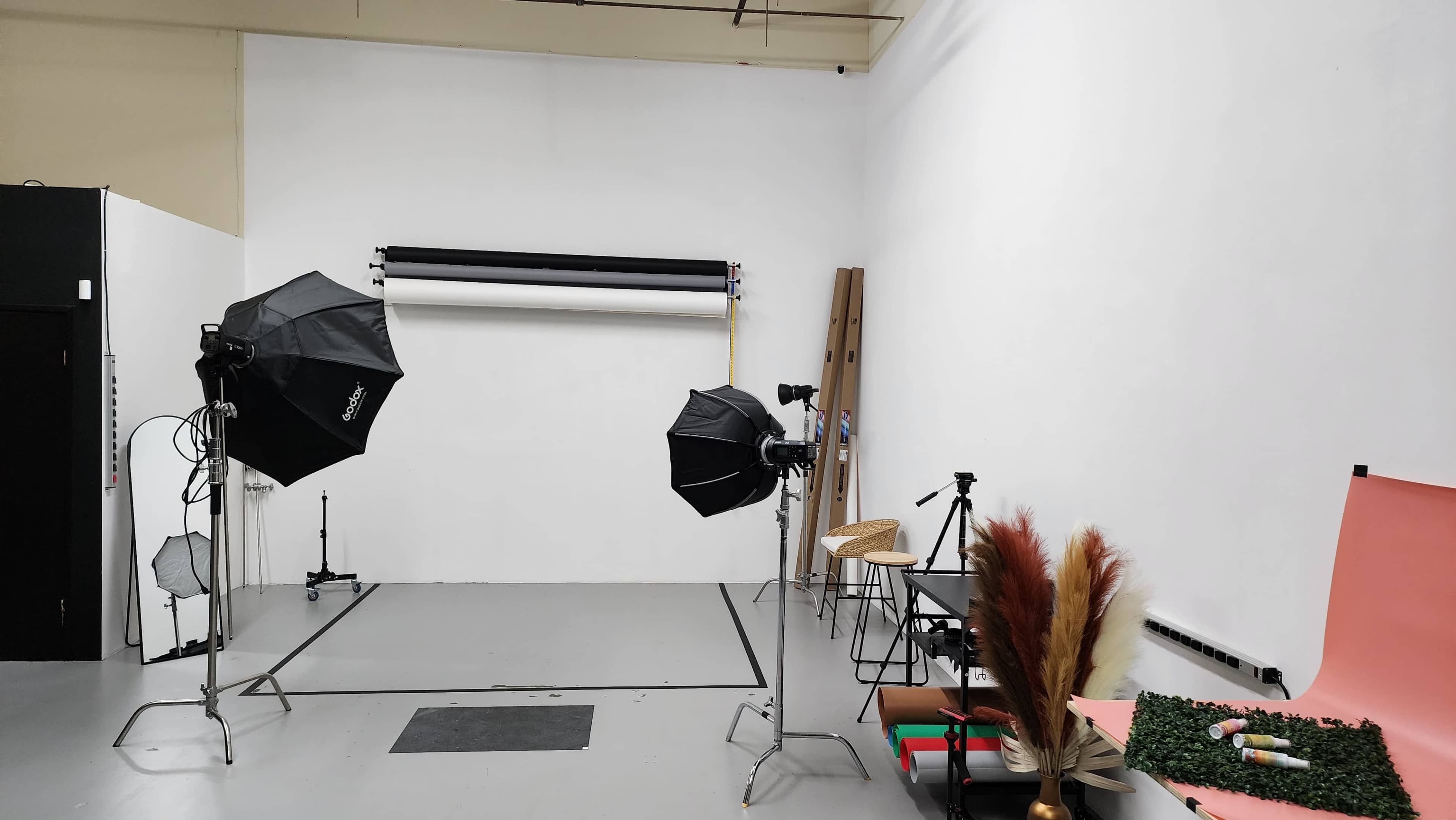 A photography studio equipped with light modifiers, backdrops, and a few props arranged on the floor.