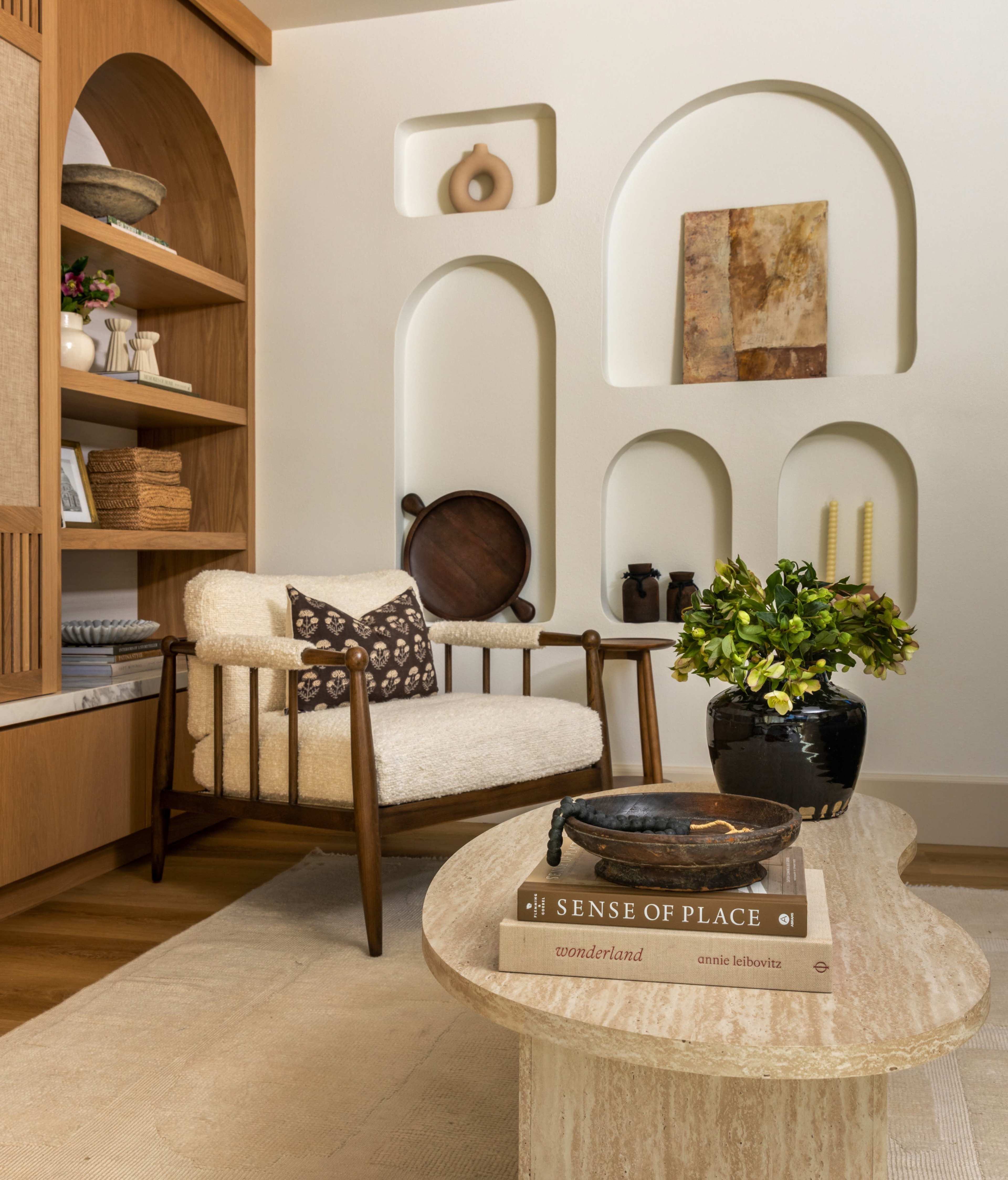 The image features a cozy living space with a comfortable chair, a decorative coffee table, and shelves showcasing various decorative items and art.