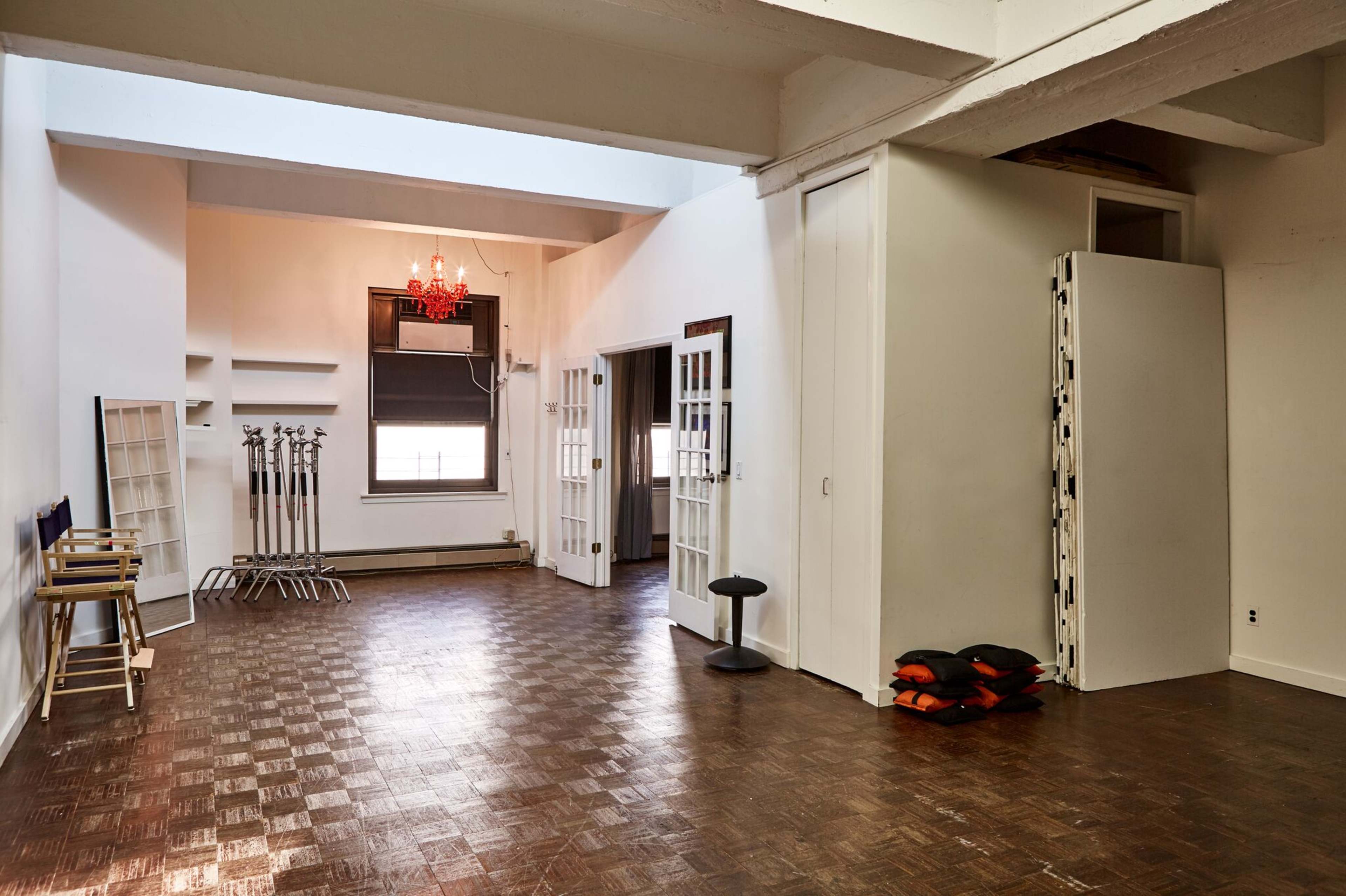 A spacious, well-lit room featuring a chandelier, folding partitions, and a few seating arrangements along the walls.