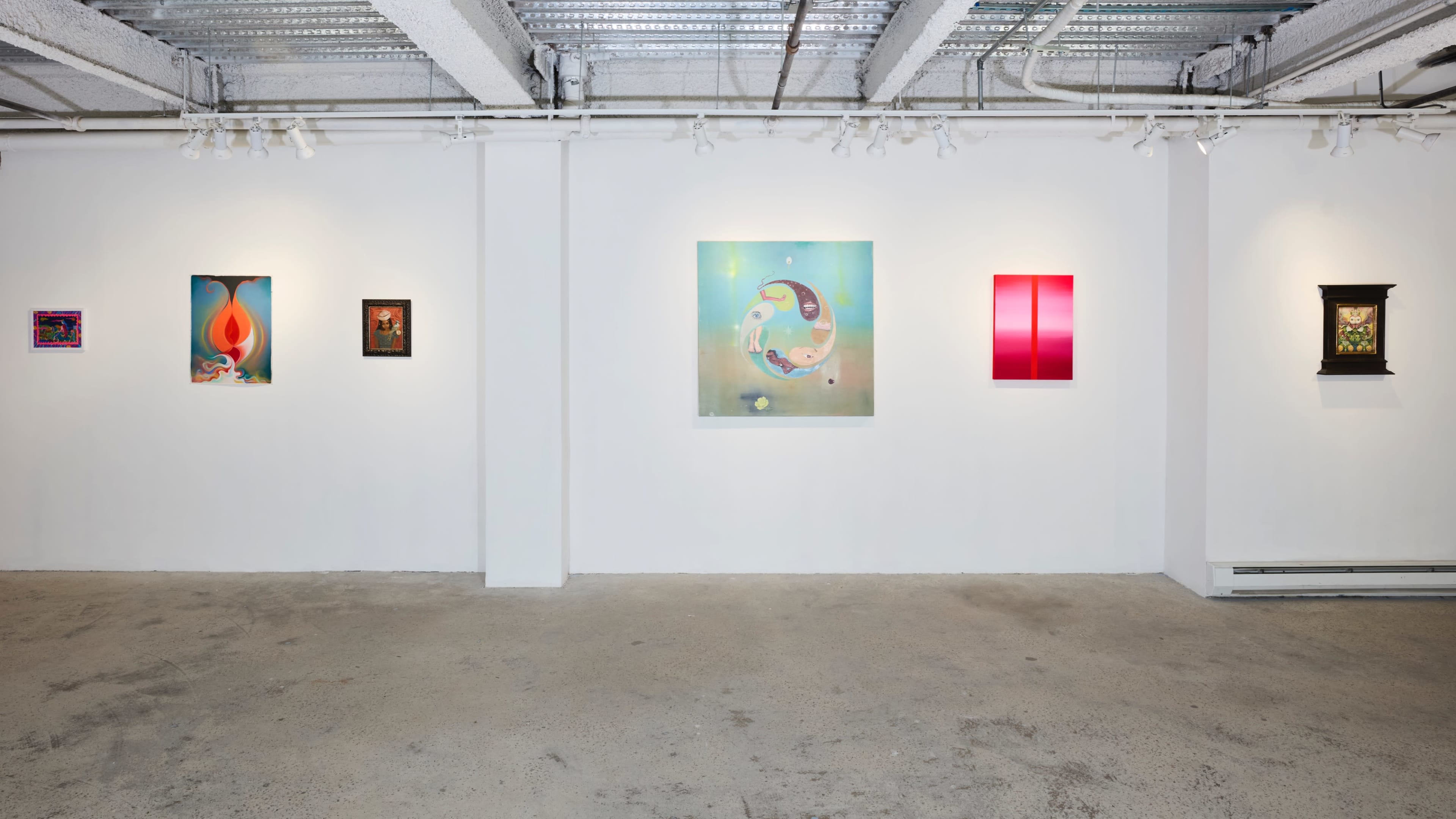 The image shows an art gallery with white walls displaying a series of colorful artworks, including paintings and framed pieces of various sizes.