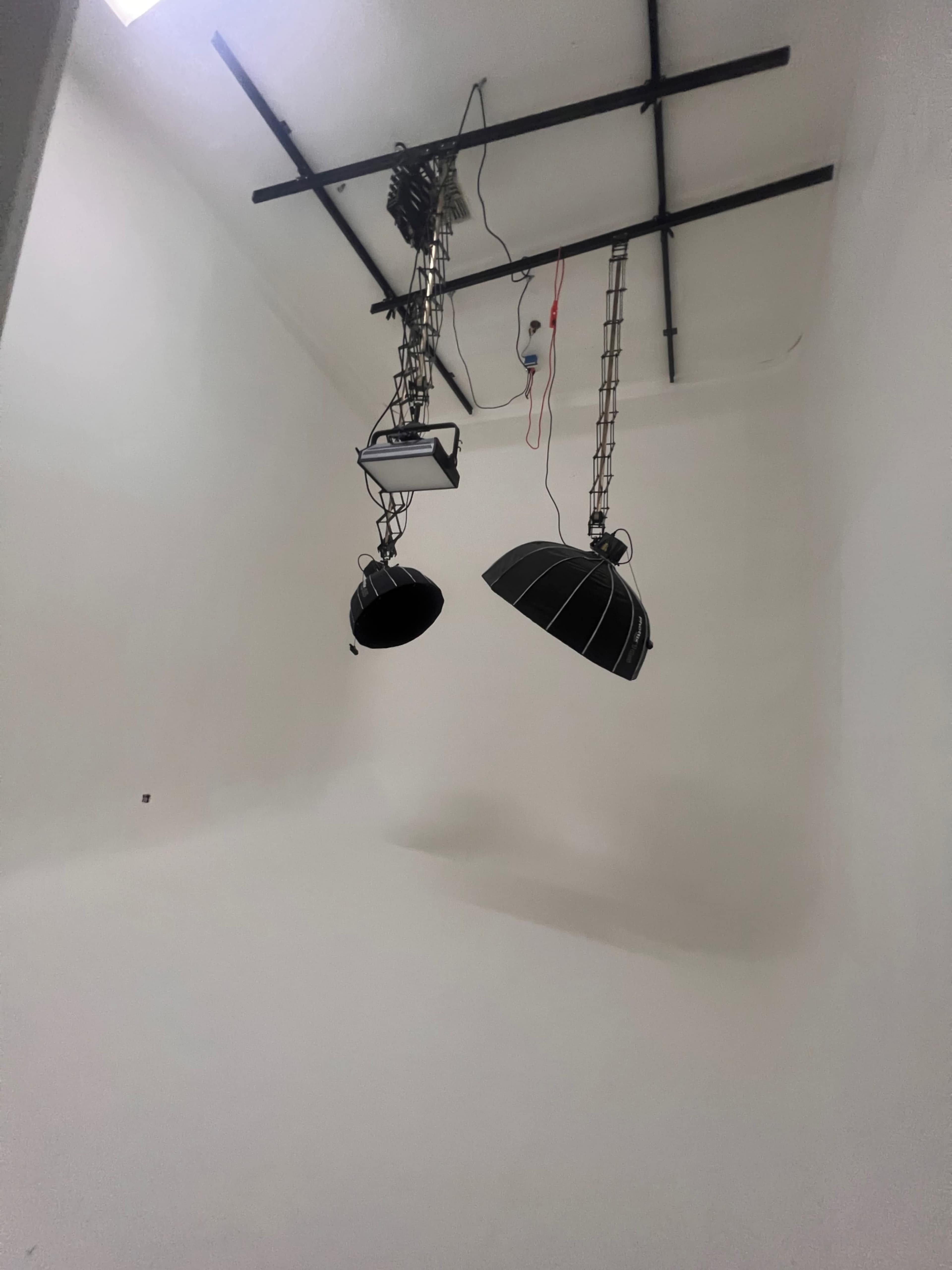 A minimalistic room with white walls and two overhead studio lights hanging from the ceiling.