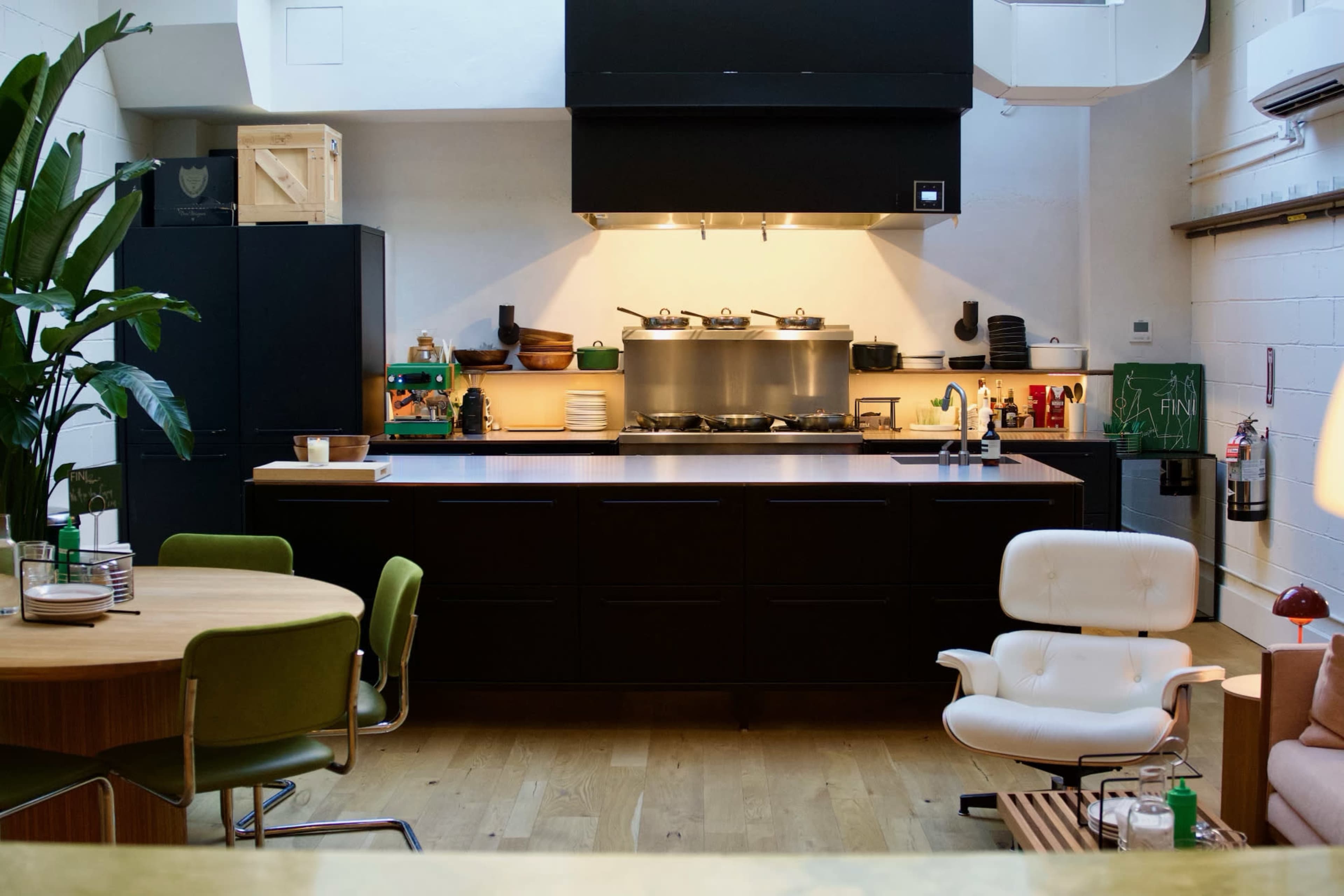 A modern kitchen and dining area featuring a dark cabinetry design, a large island, and a round dining table.