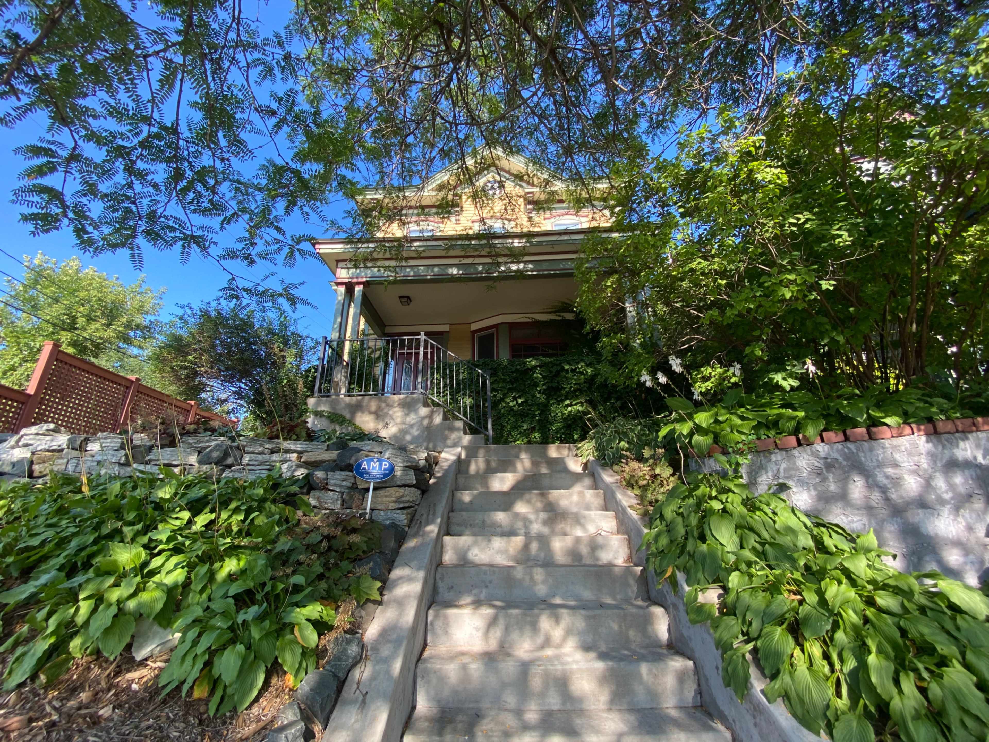 A staircase leads up to a house surrounded by greenery and trees.