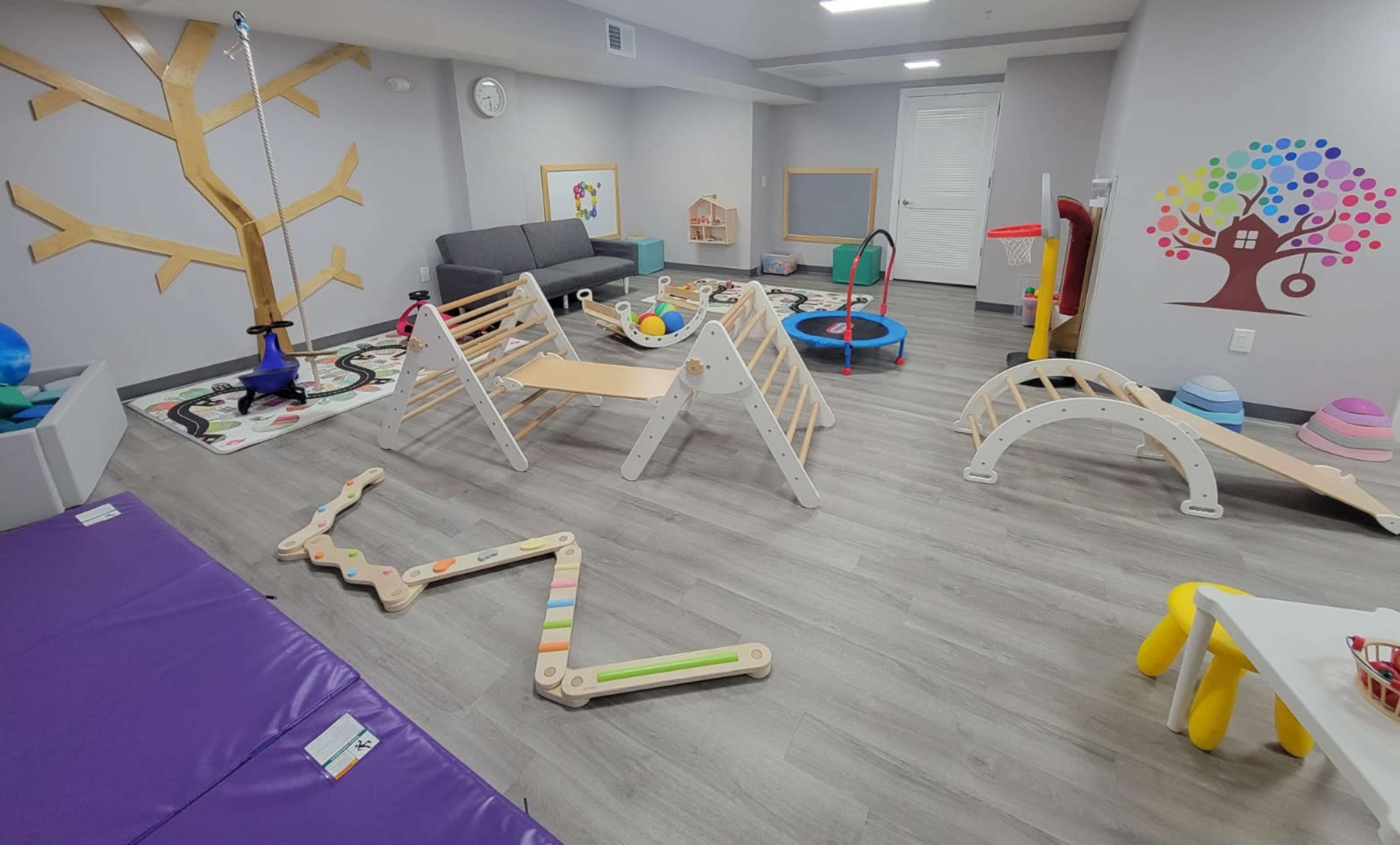 A playroom filled with various children's toys, climbing structures, and colorful mats.