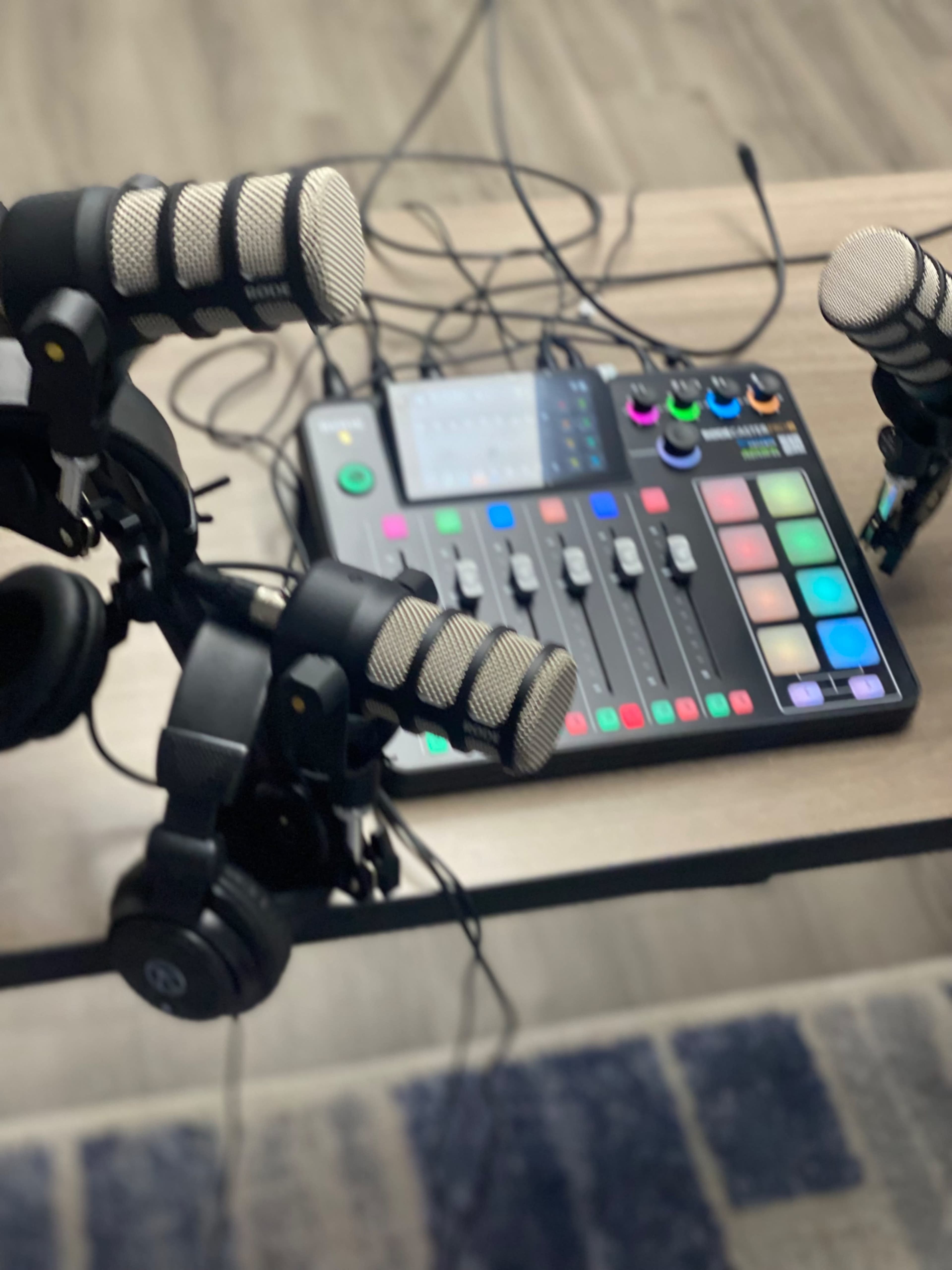 A tabletop audio mixing device with two microphones and headphones positioned nearby.