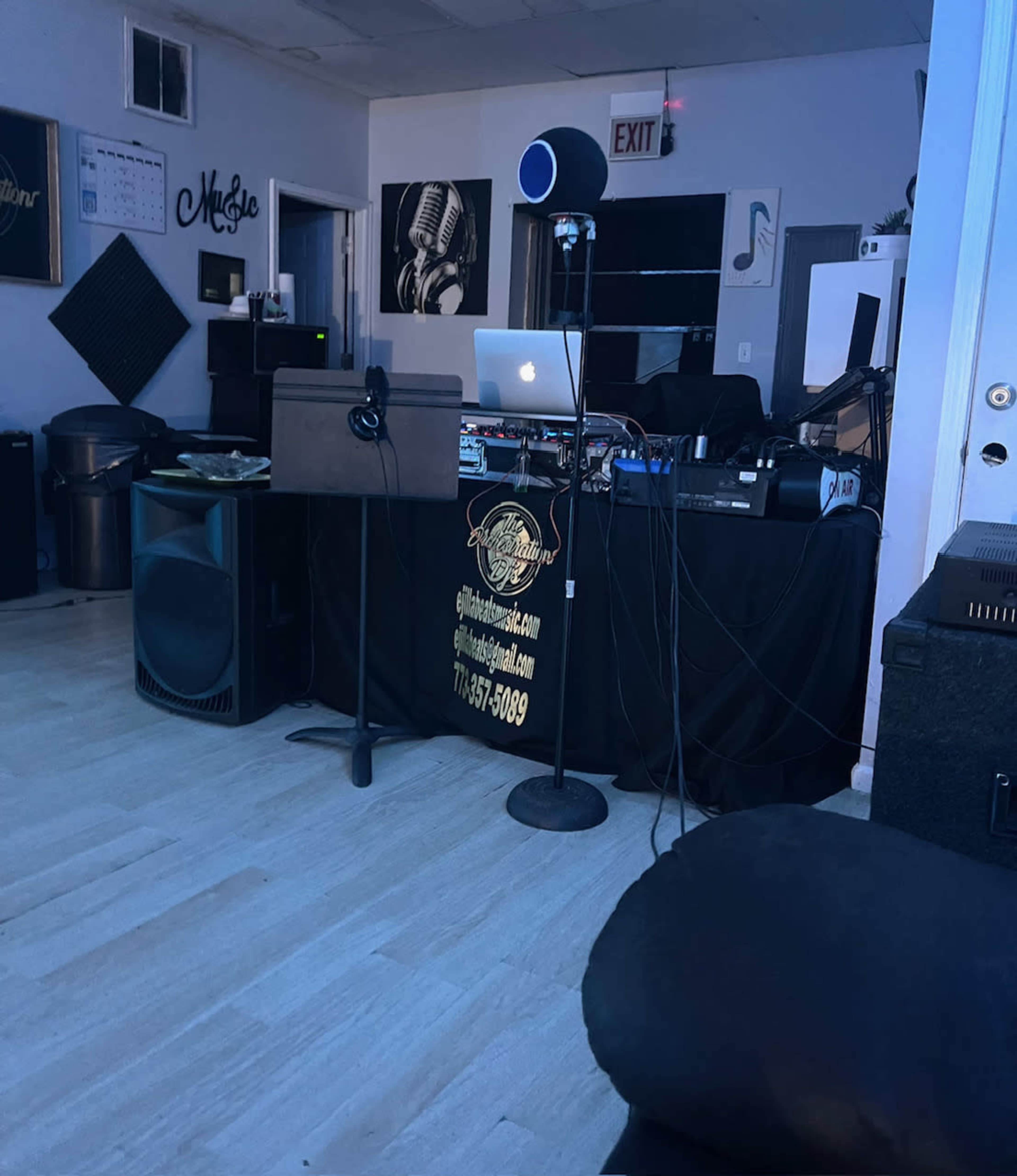 A DJ setup with a microphone and equipment in a dimly lit room featuring music-themed decorations.