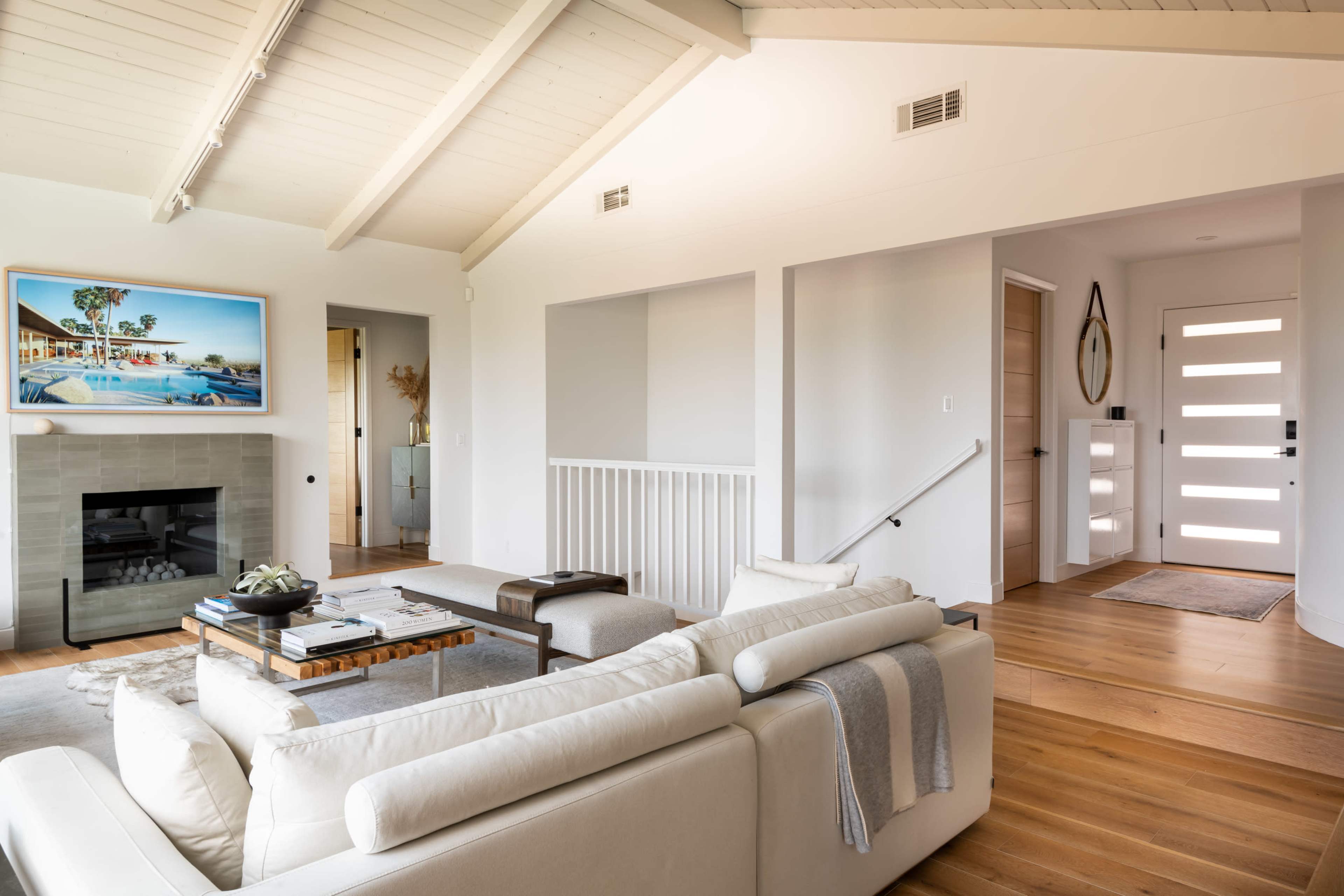 A modern living room with vaulted ceilings, a fireplace, and a door leading to a hallway.
