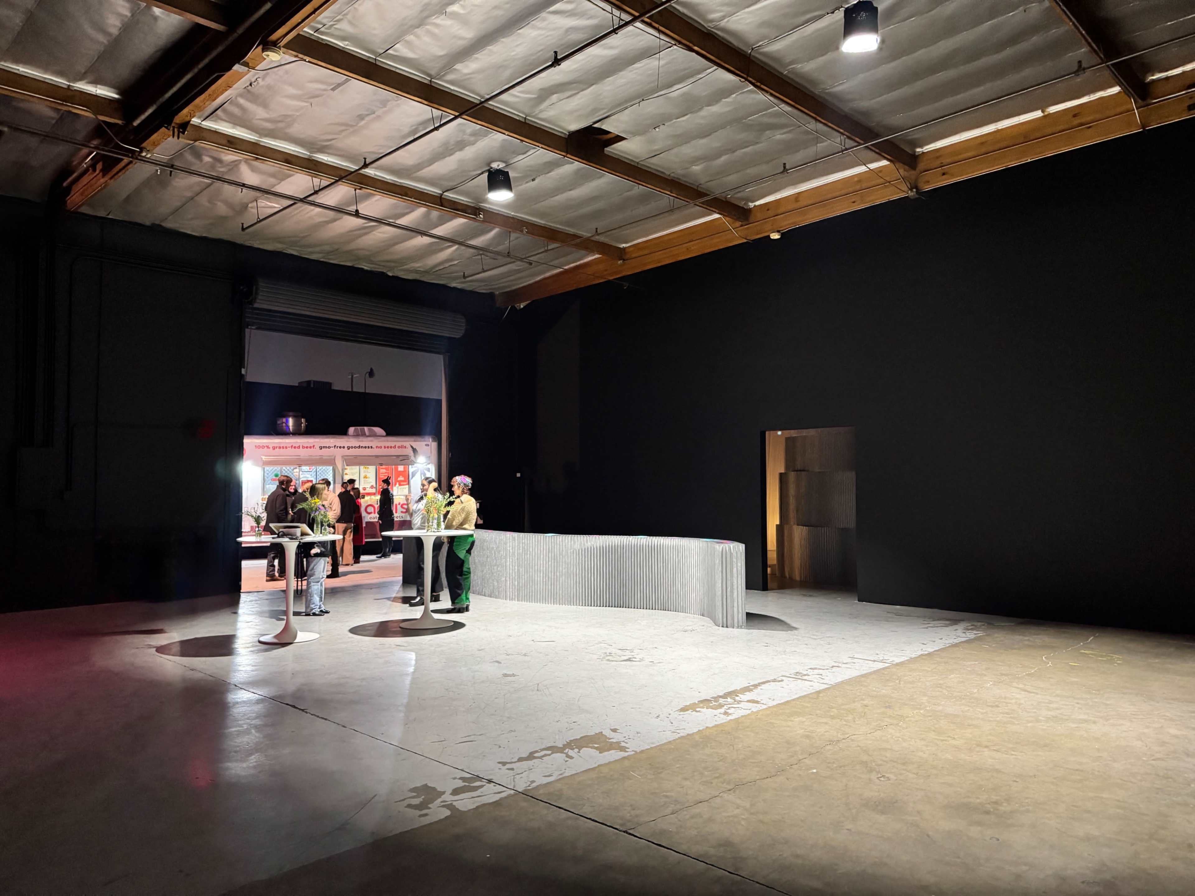 The image shows a spacious, dimly lit industrial room with a large gray counter and a few people standing near it.