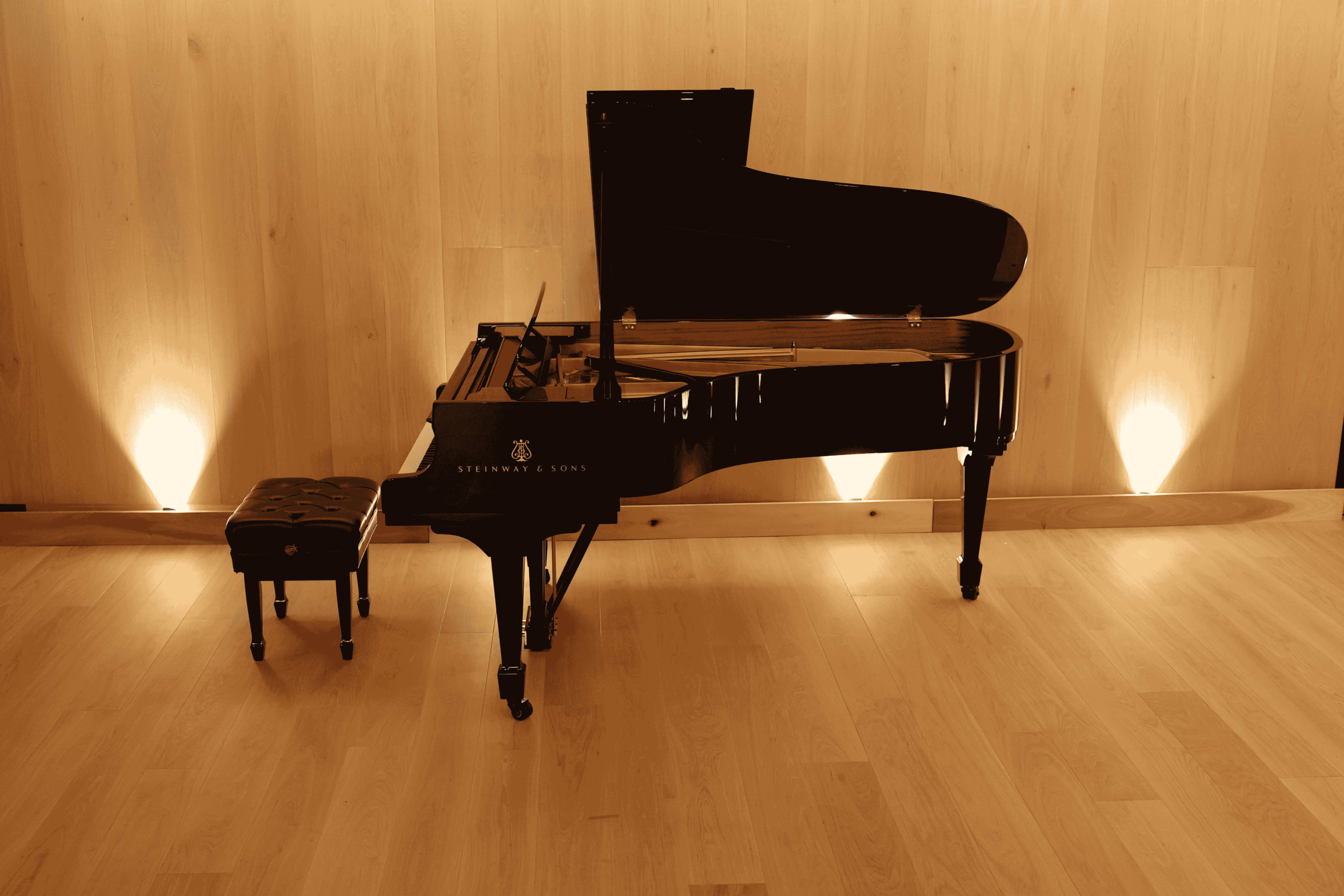 A grand piano is positioned in a well-lit room with wooden walls and warm lighting.