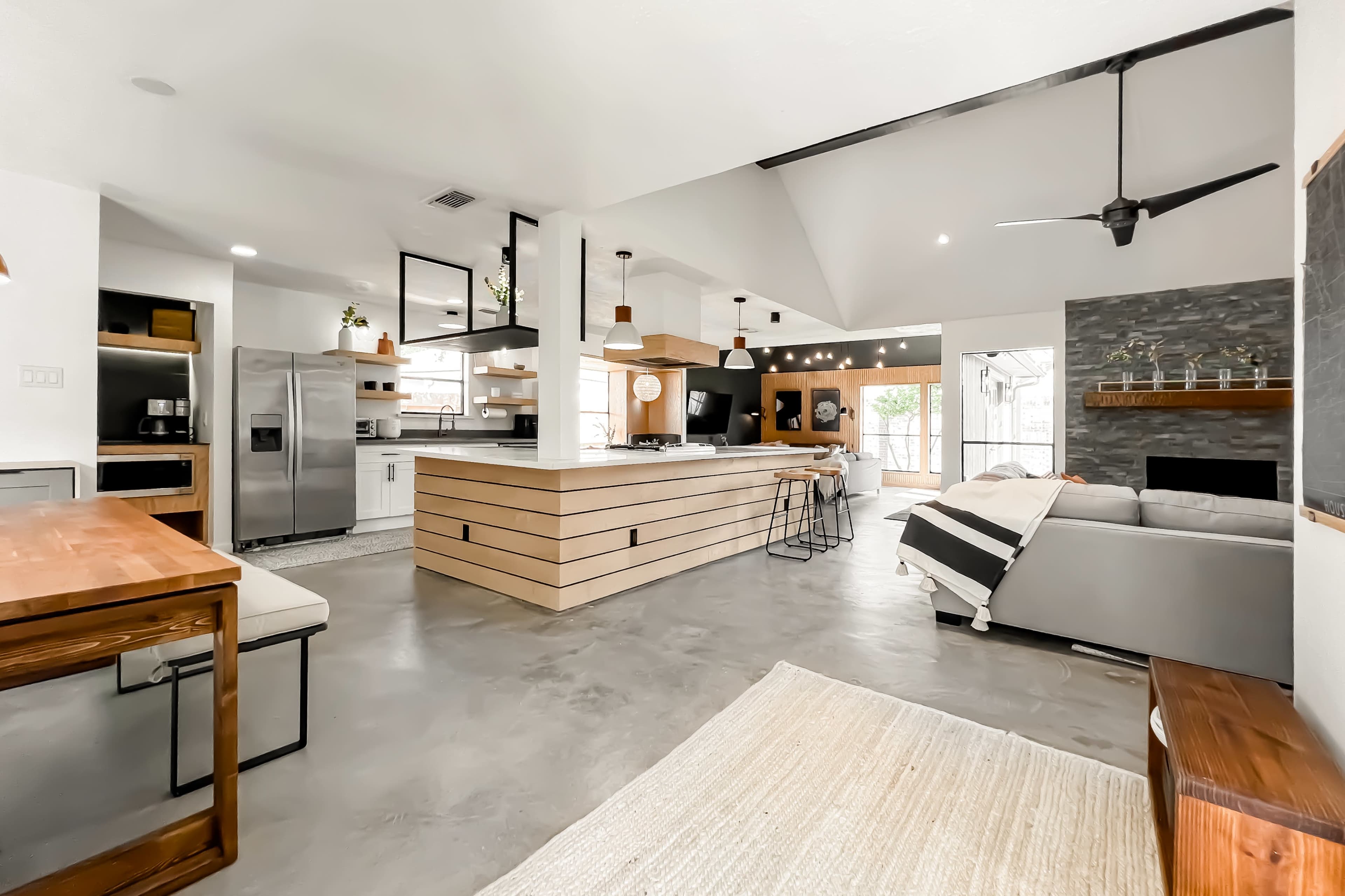 A modern kitchen and living area featuring an open layout with a large island, a dining table, and a cozy seating area.