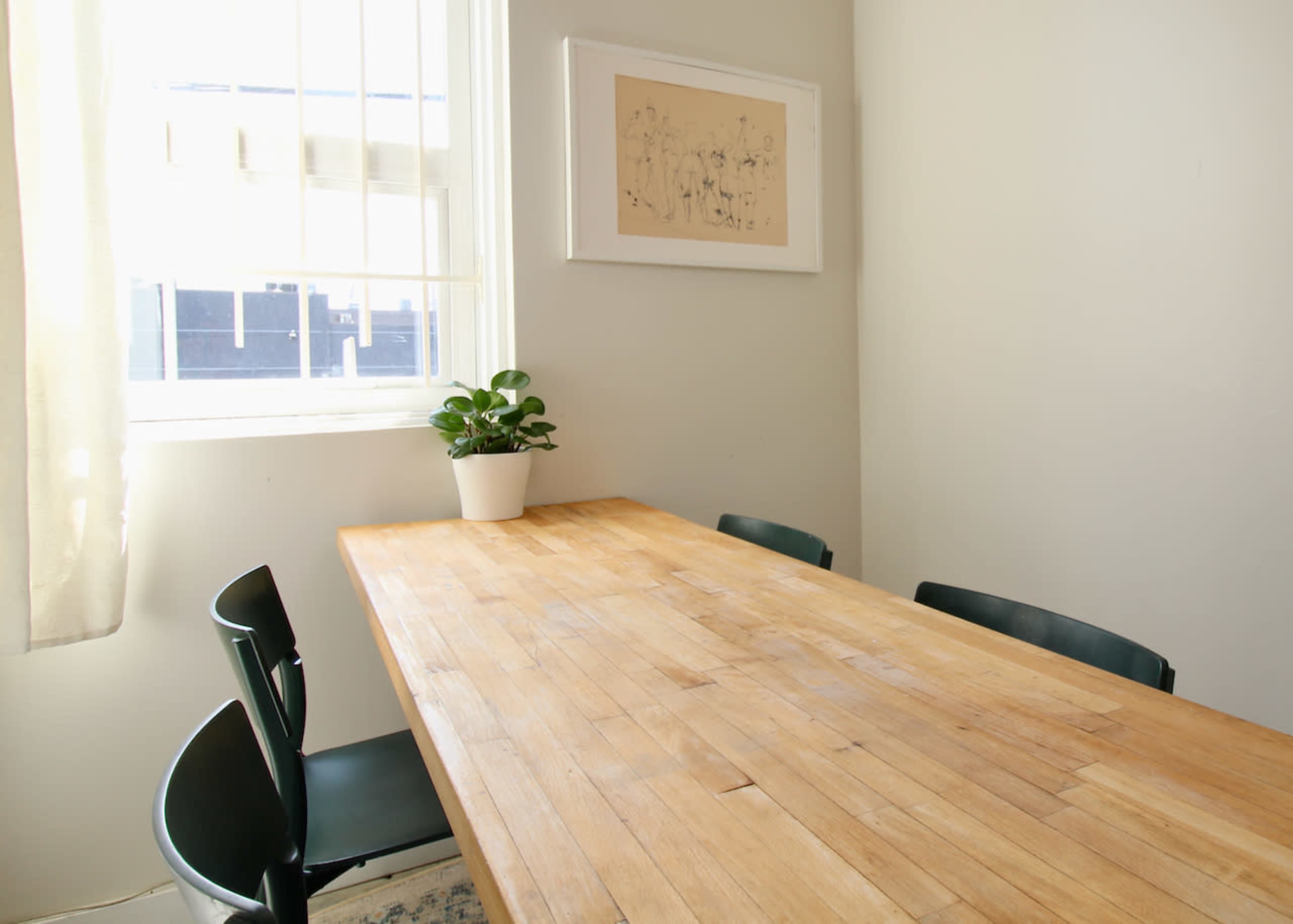 A wooden dining table is positioned near a window, accompanied by four black chairs and a small potted plant on the table.