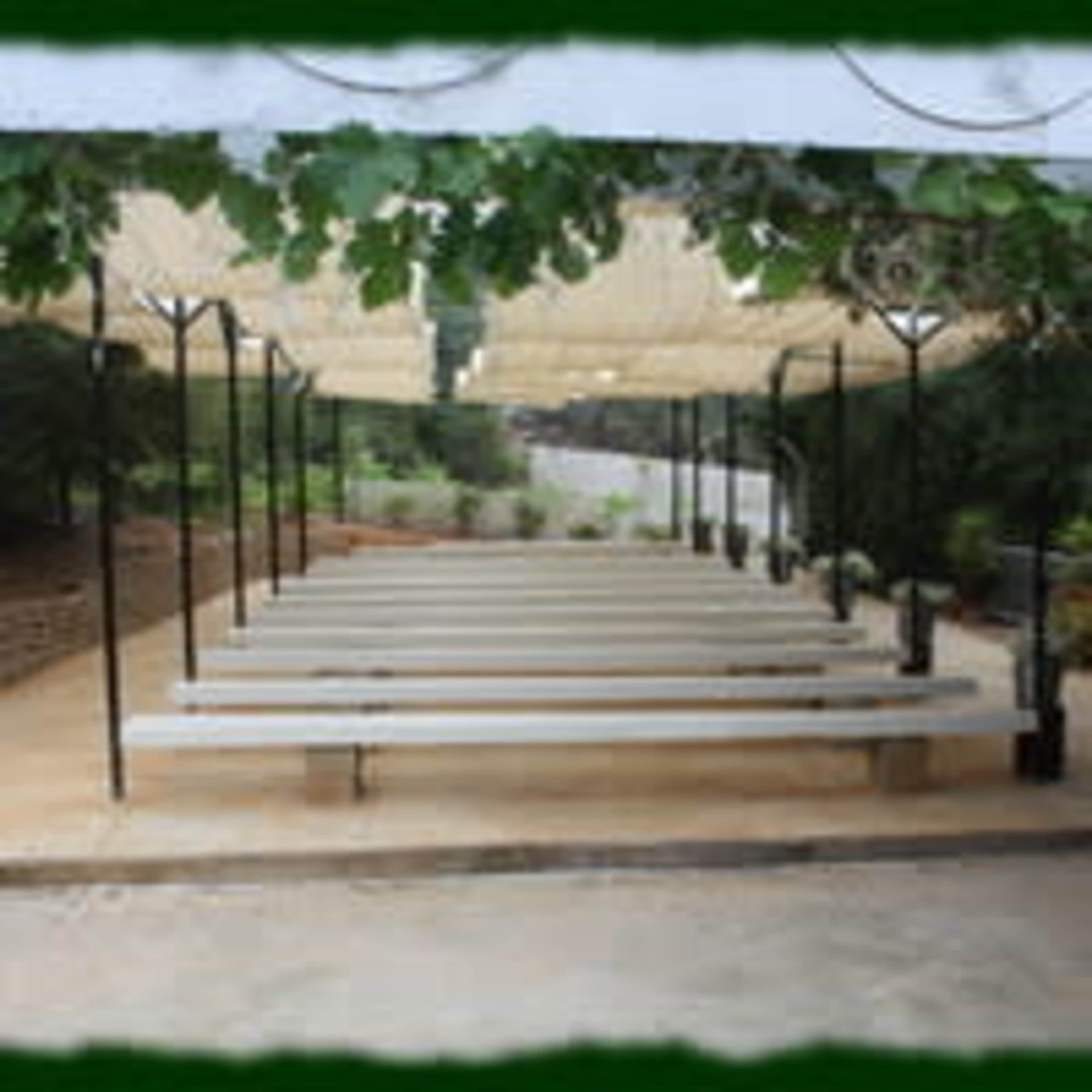 A shaded seating area with long benches arranged in rows under a canopy of fabric.
