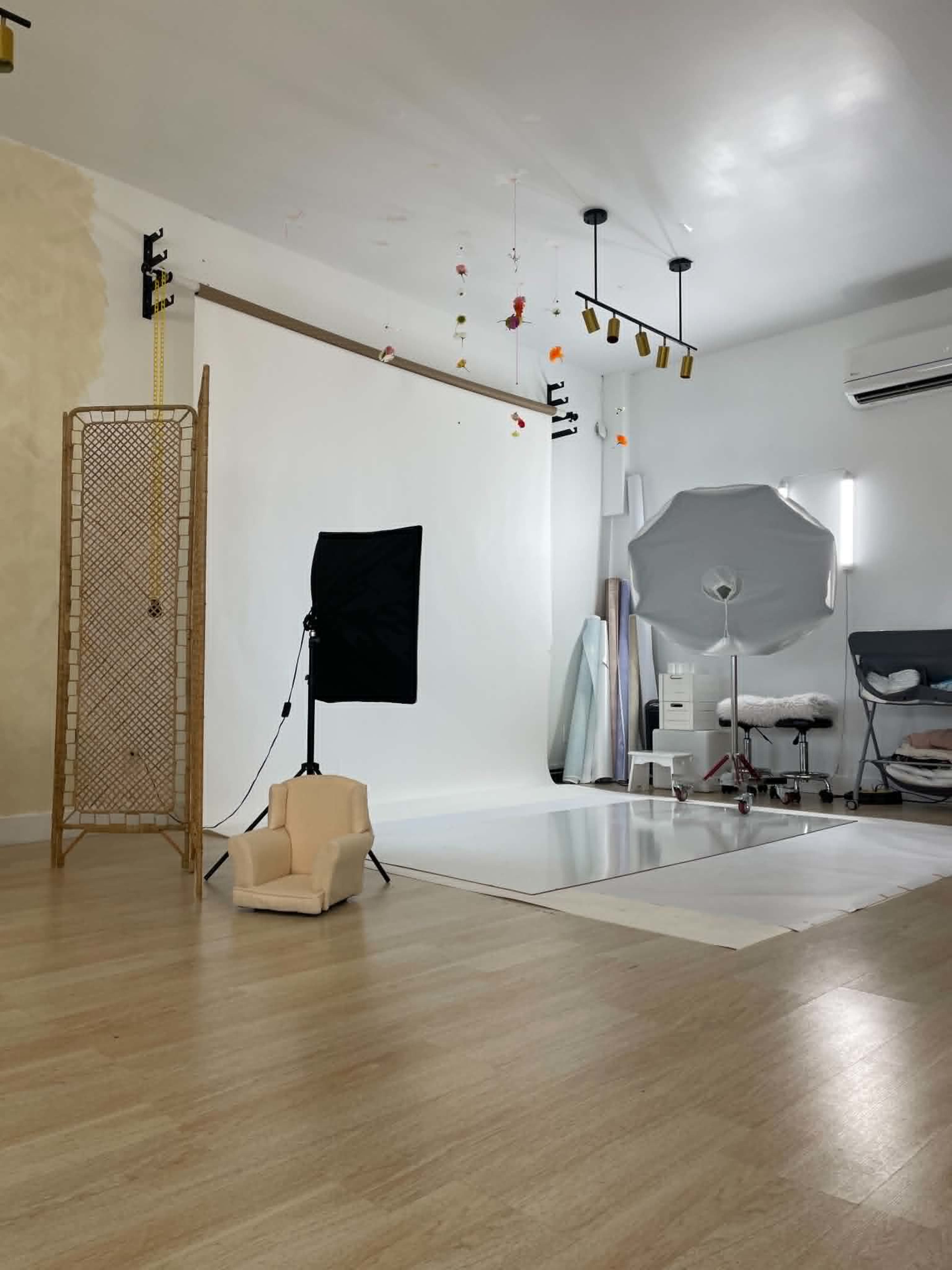 The image shows a well-lit photography studio featuring a backdrop, lighting equipment, and a variety of props and materials arranged on the floor.